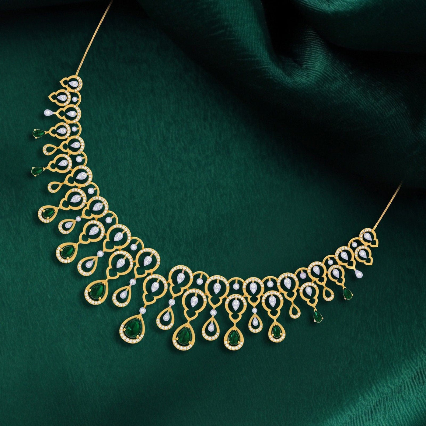 Gold necklace with emerald gemstone stones on a dark green fabric background