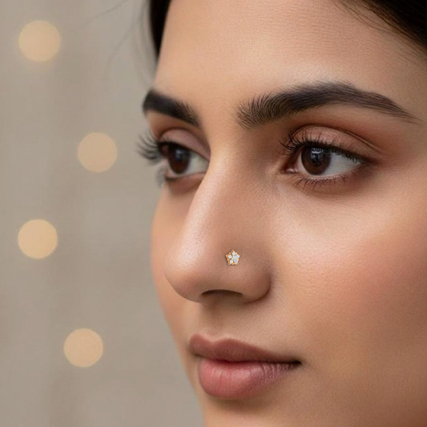 Close-up of a woman's face with a gold nose pin against a neutral background