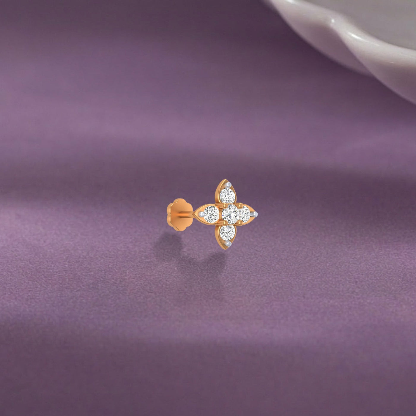 yellow gold and diamond stud nose pin with diamonds on a purple fabric background