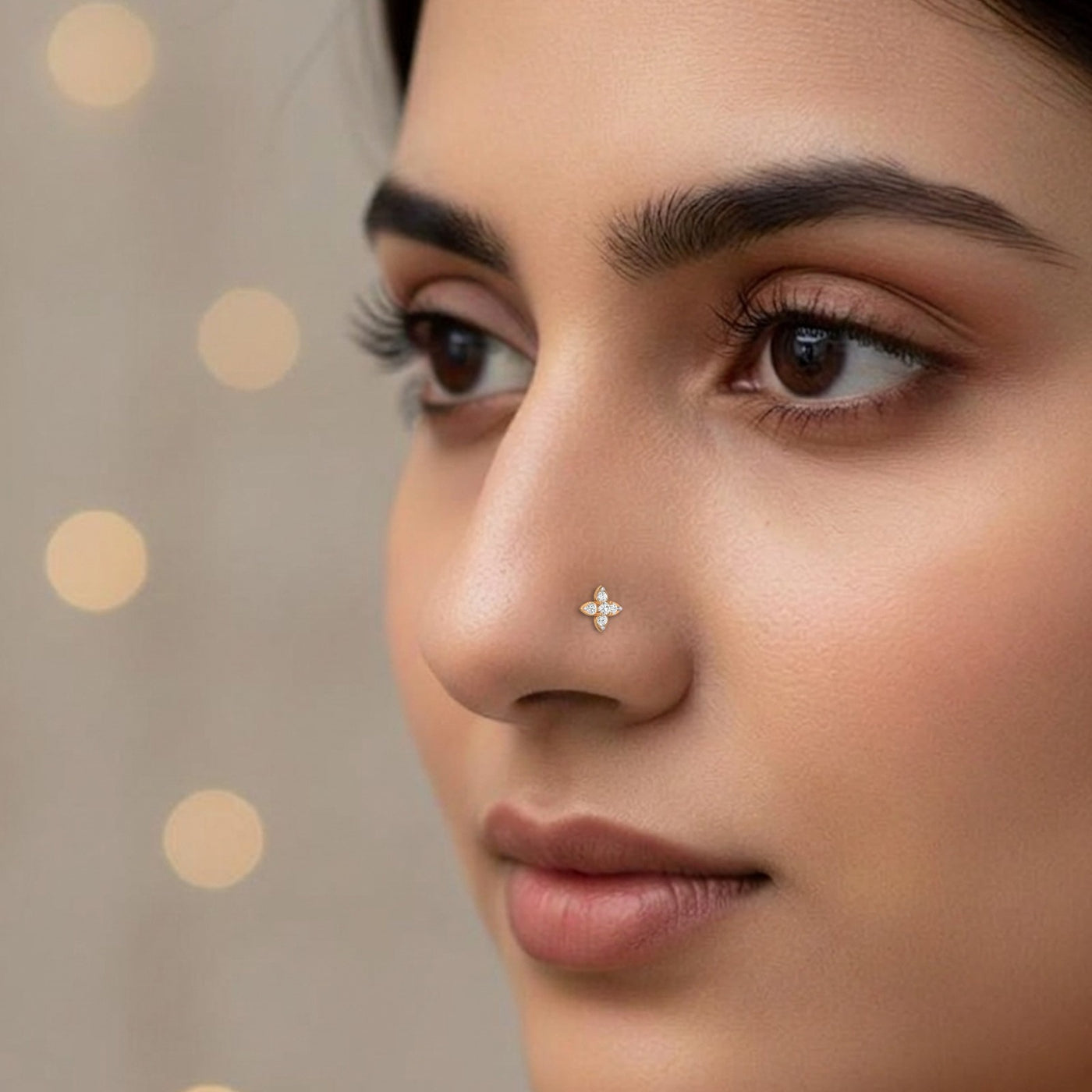 Close-up of a woman's face with a nose pin against a neutral background