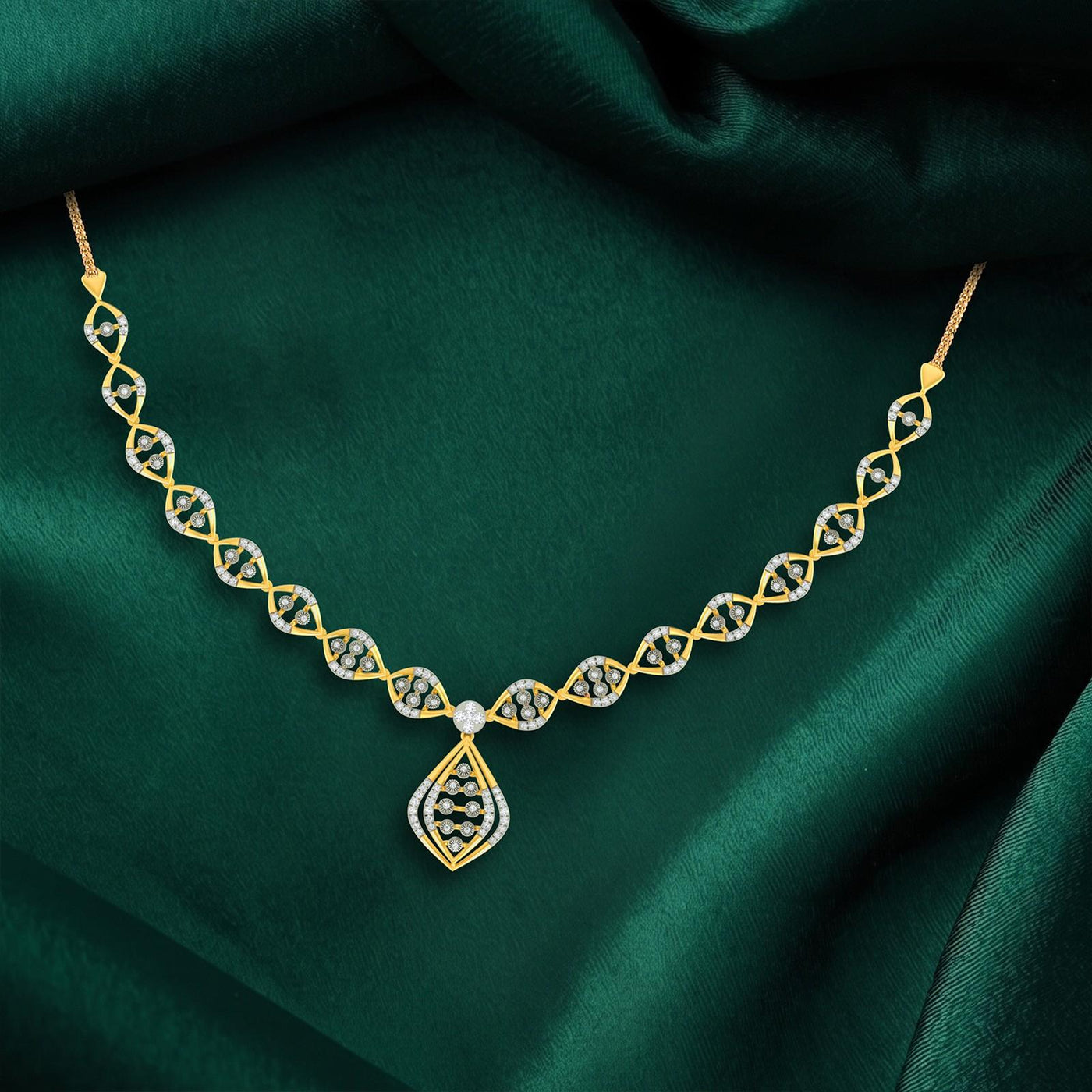 Gold necklace with a teardrop and diamond-encrusted links, displayed on a draped dark green satin fabric.
