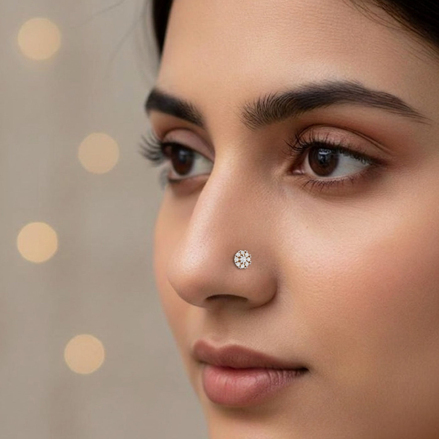 Close-up of a woman's face with a diamond nose pin against a neutral background