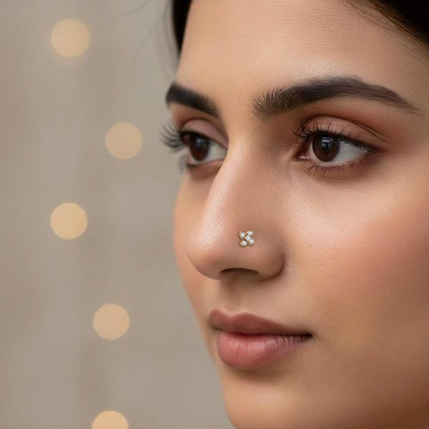 Close-up of a woman's face with a gold nose pin against a neutral background