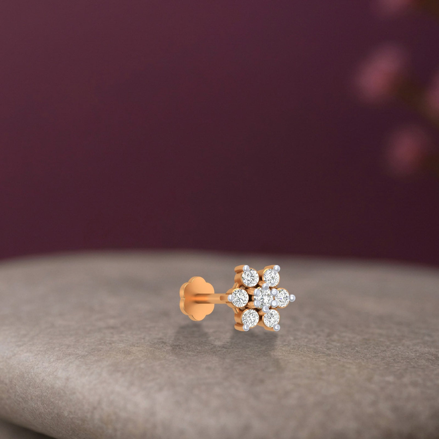 yellow gold and diamond stud nose pin  with diamonds on a gray surface and purple background