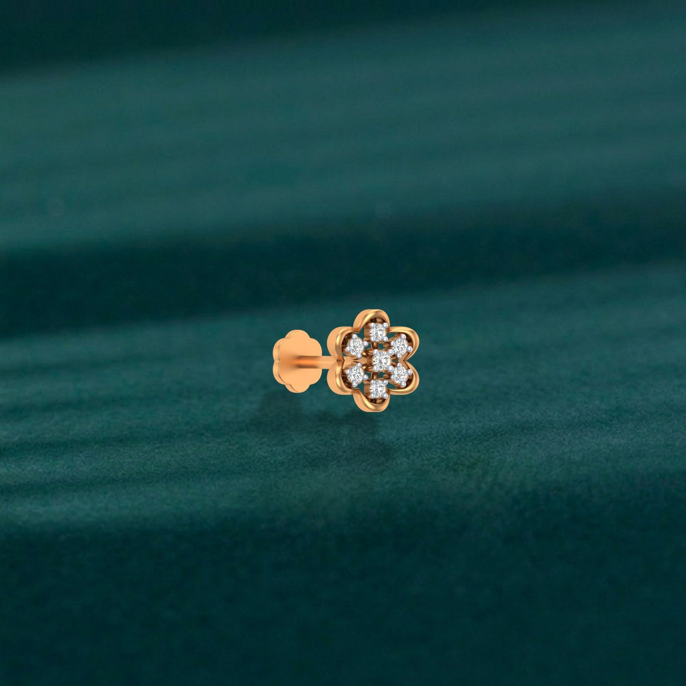 yellow gold and diamond stud nose pin on a teal fabric background