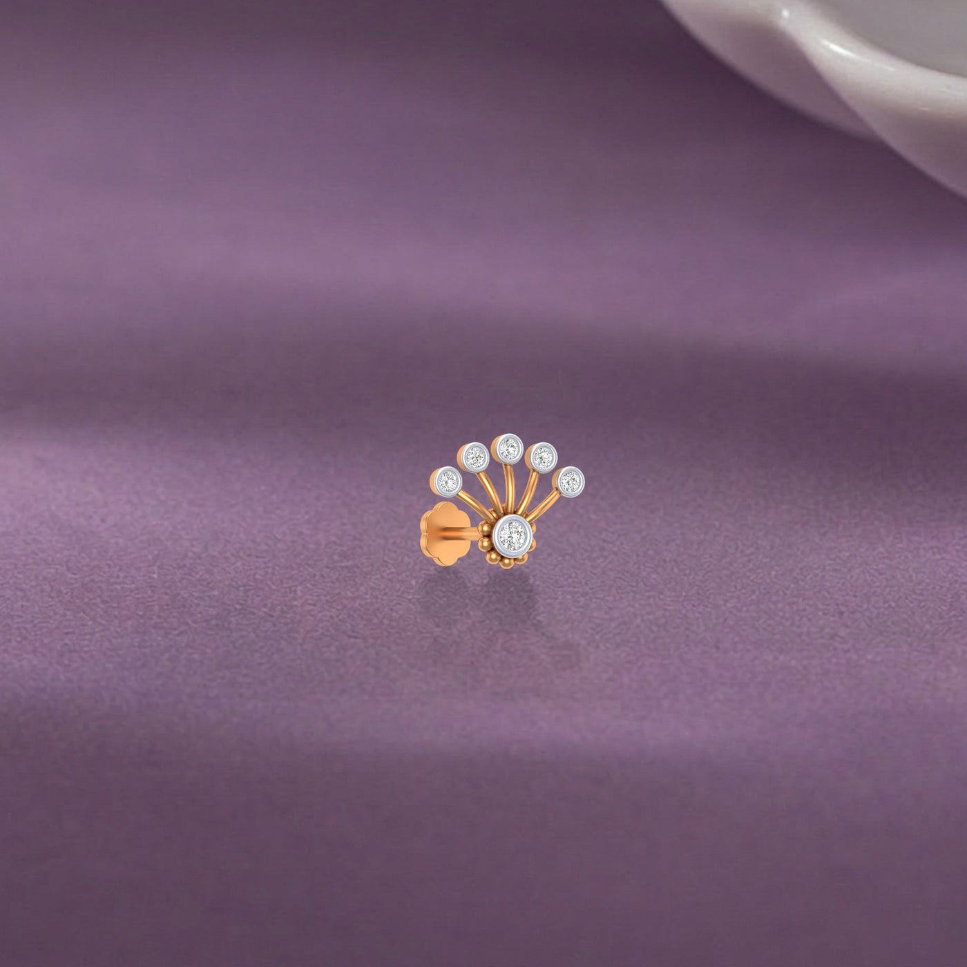 yellow gold and stud nose pin with multiple small diamonds on a purple fabric background