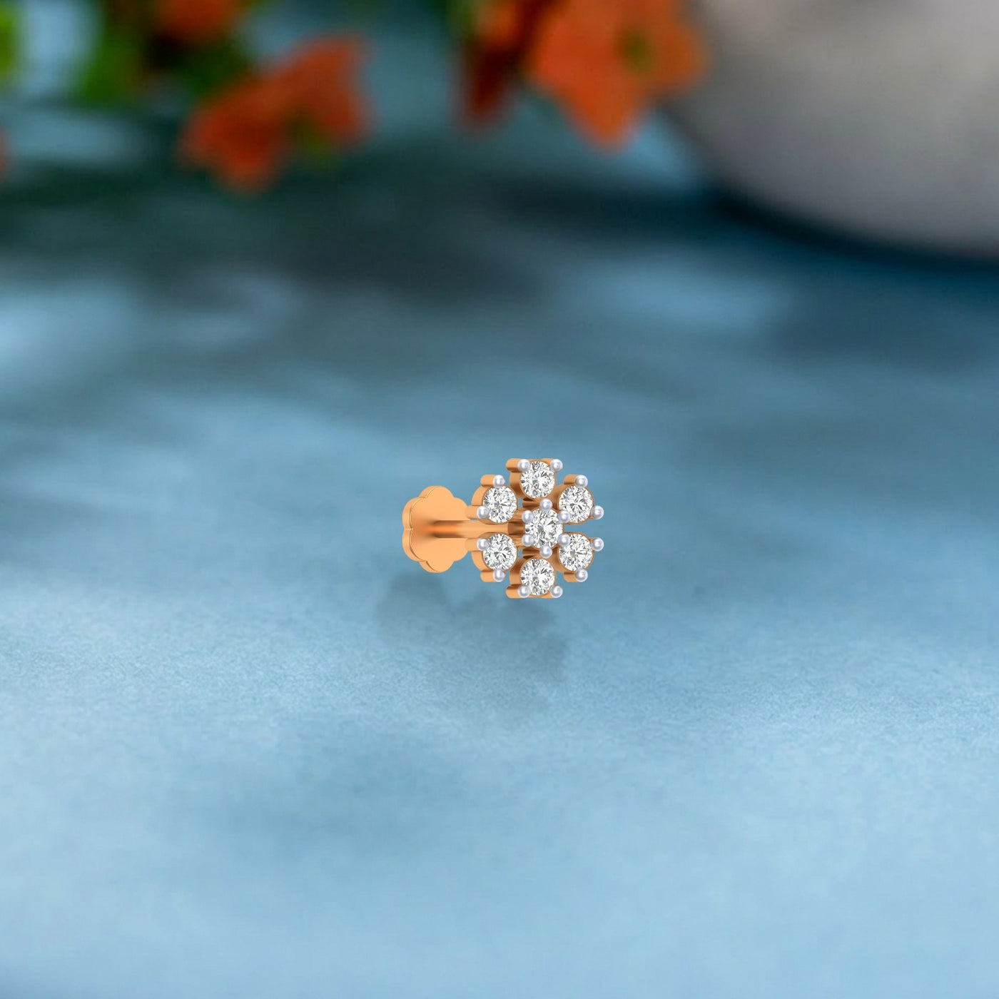 yellow gold and diamond stud nose pin on a light blue fabric background