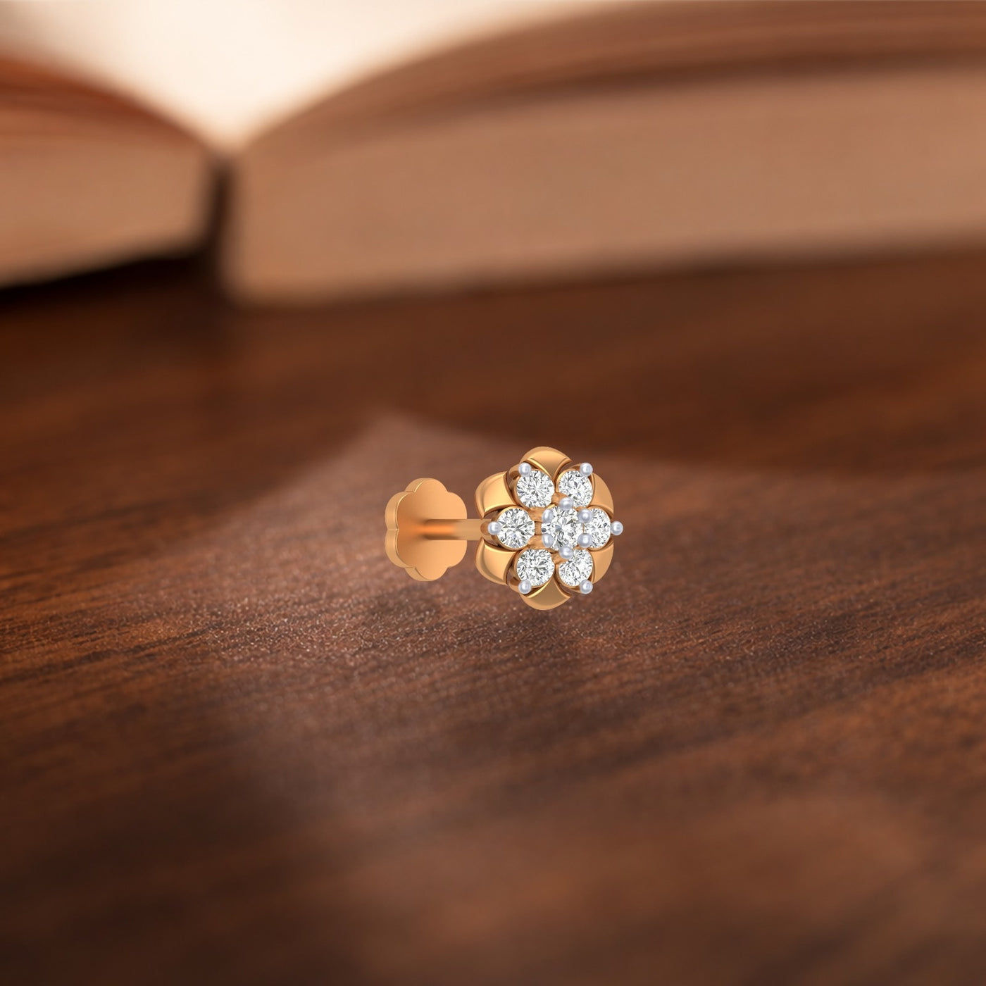 yellow gold and diamond nose pin with floral design on a wooden surface