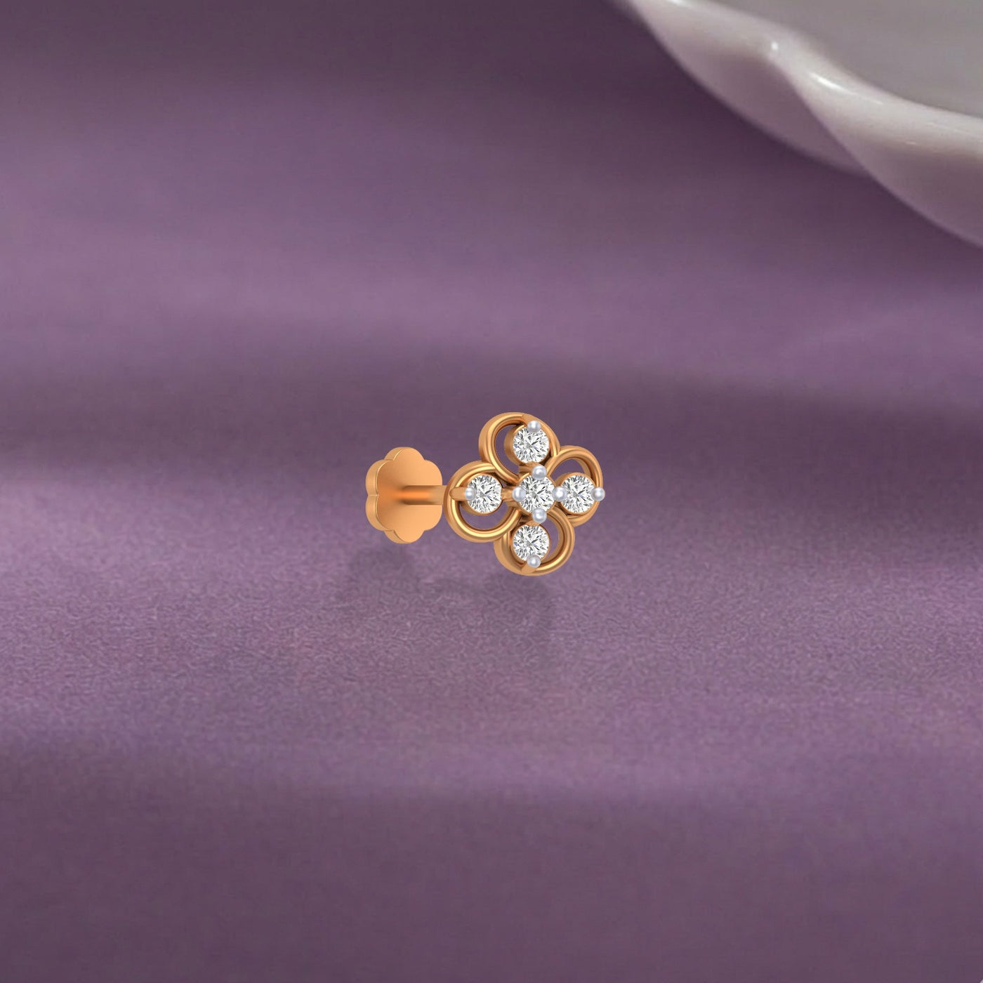 yellow gold and diamond stud nose pin on a purple fabric background