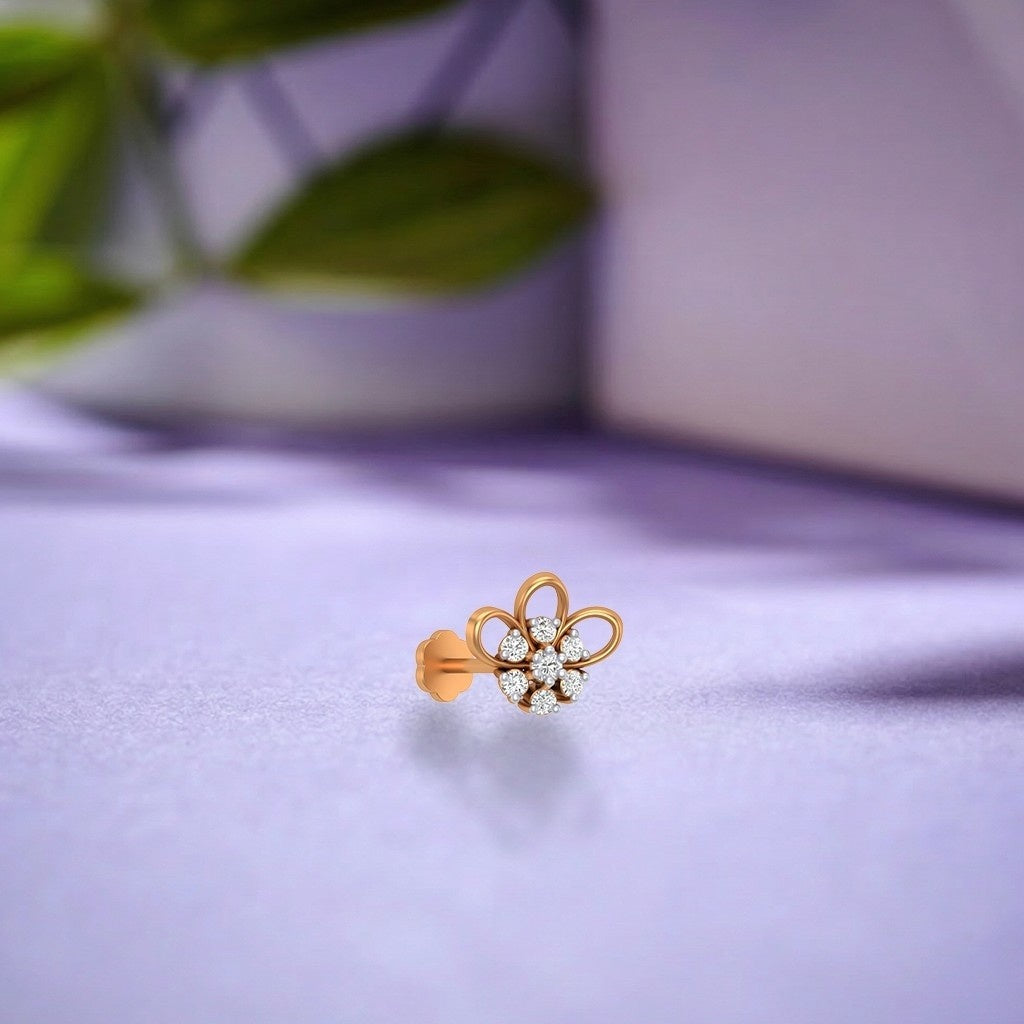 yellow gold and diamond stud nose pin with floral design on a purple surface