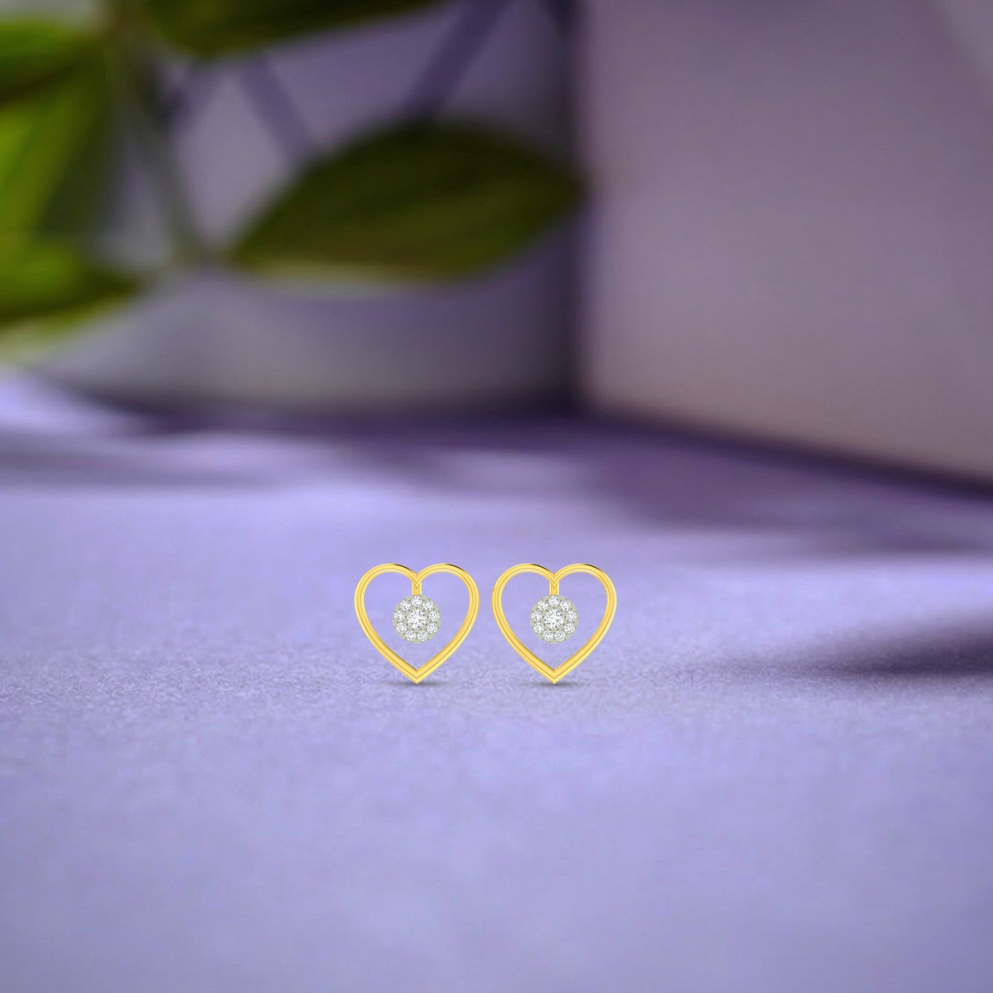 Gold and diamond heart-shaped earrings on a purple fabric background.
