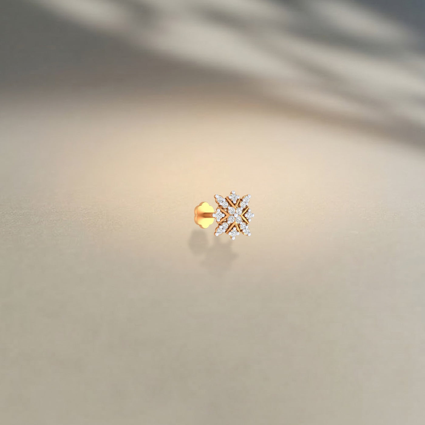 Yellow Gold and diamond stud nose pin snowflake-shaped earring on a beige background