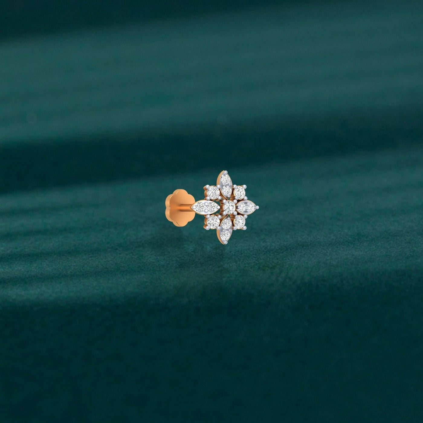 yellow gold and diamond stud nose pin on a green fabric background