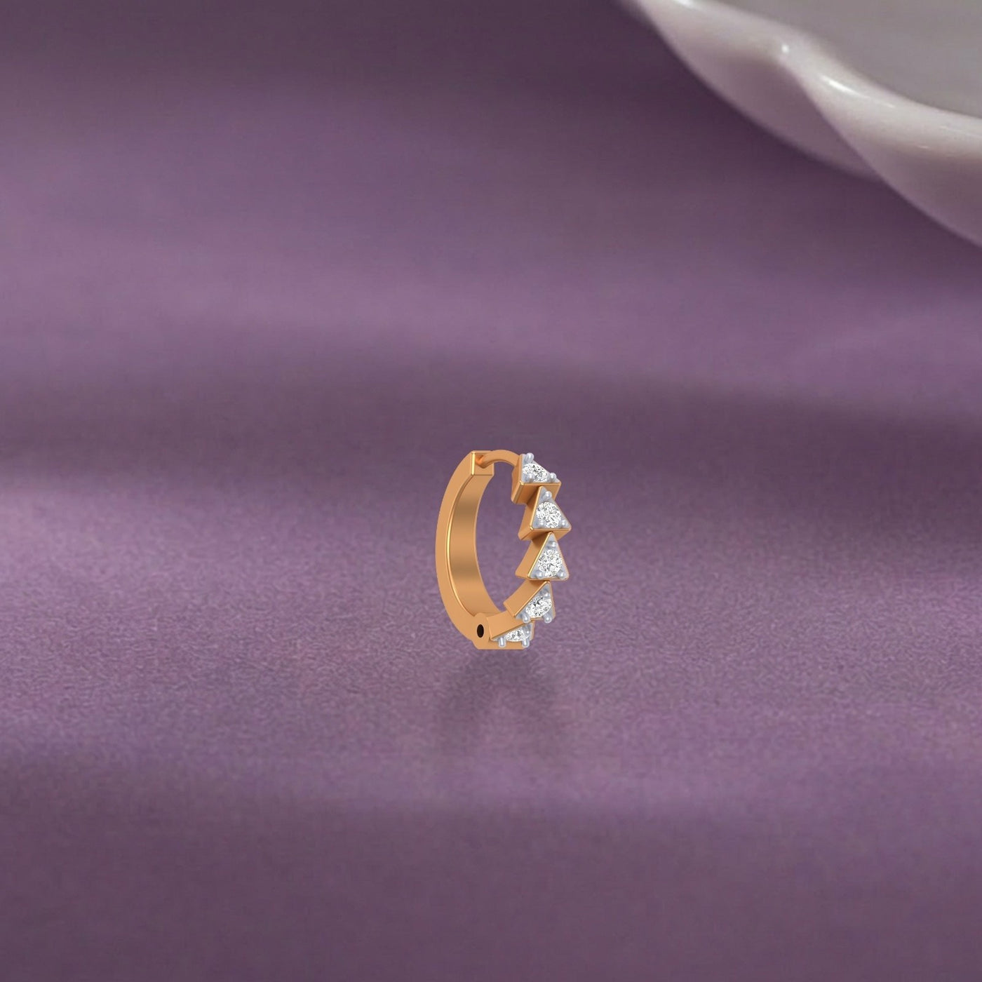 yellow gold and diamond nose ring with diamonds on a purple fabric background