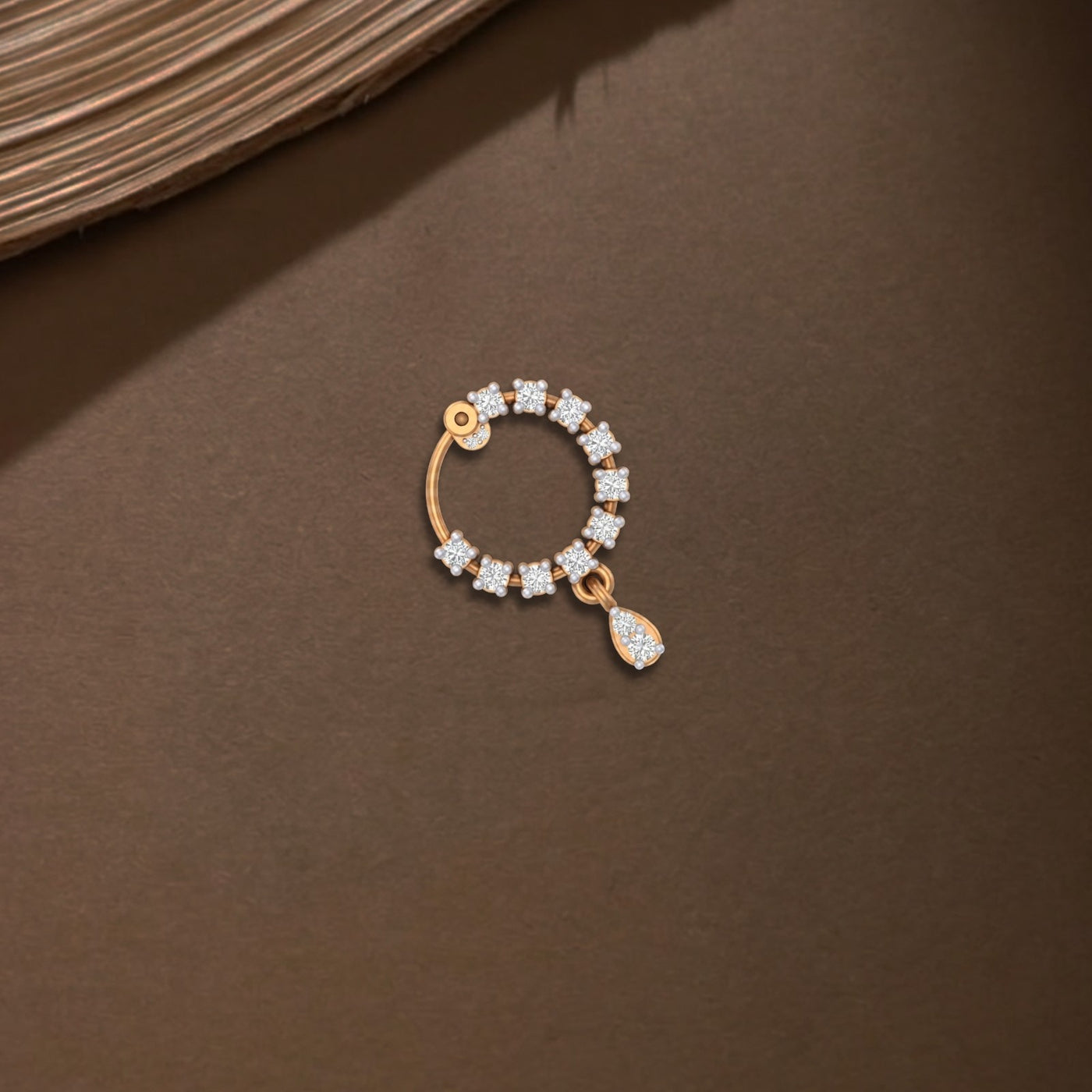 Yellow Gold and diamond nose ring on a brown surface