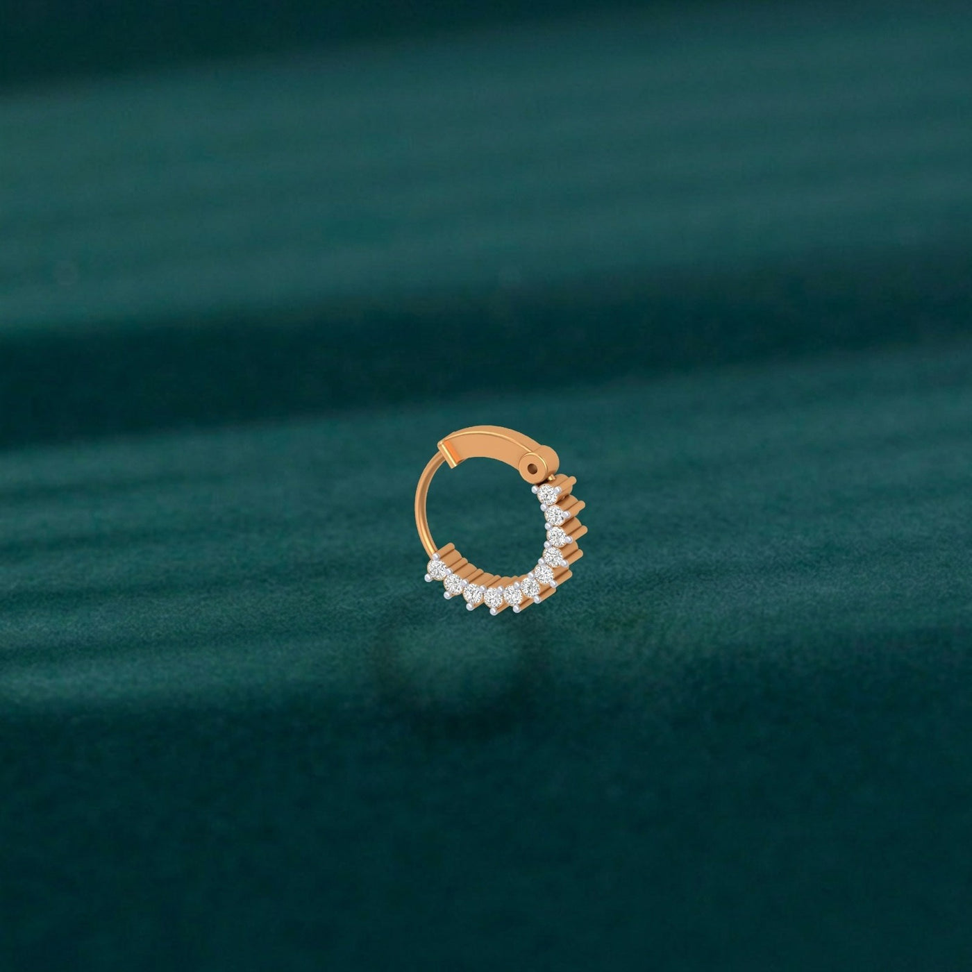 yellow gold and diamond nose ring with diamonds on a green fabric background