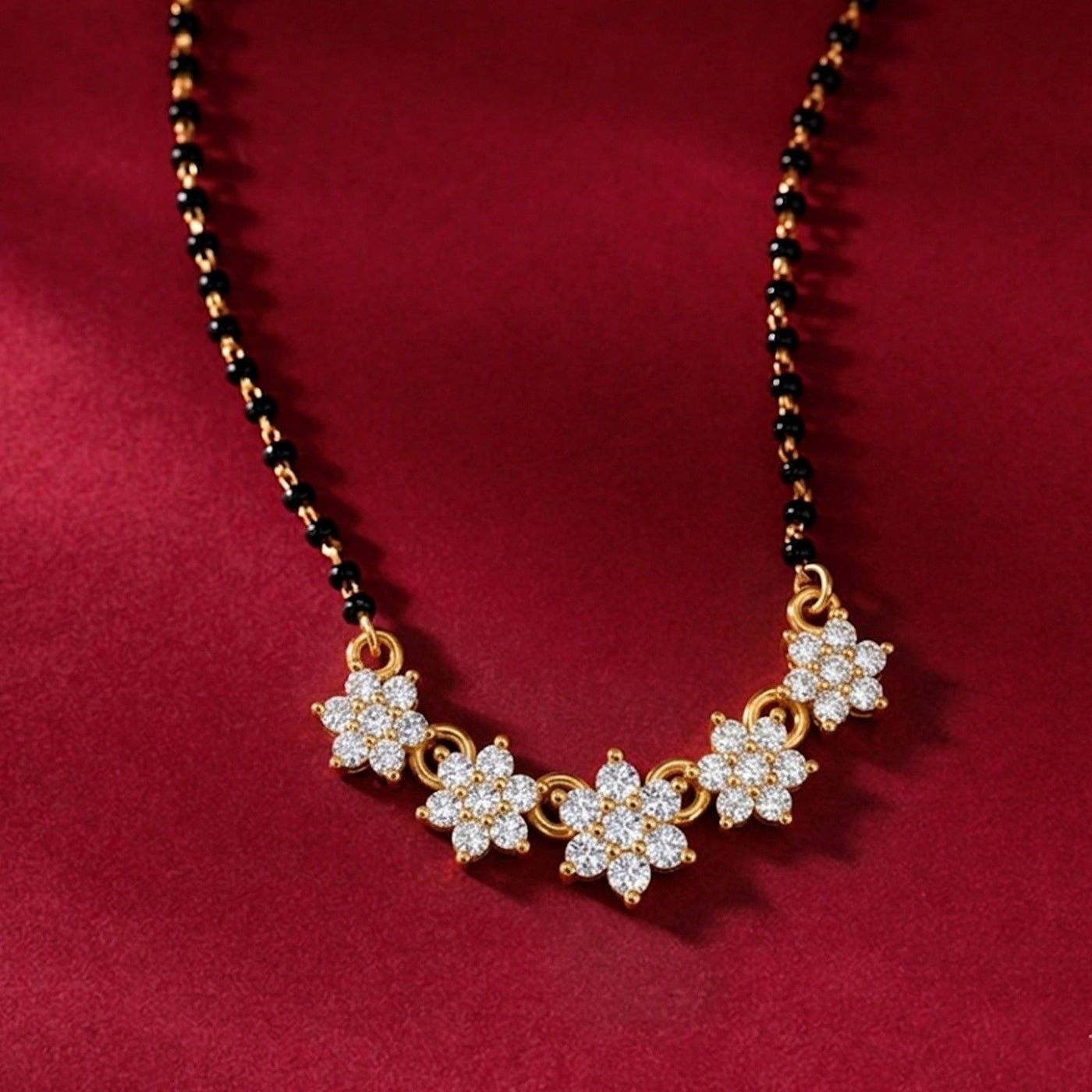 gold and diamond mangalsutra with dark red fabric background.