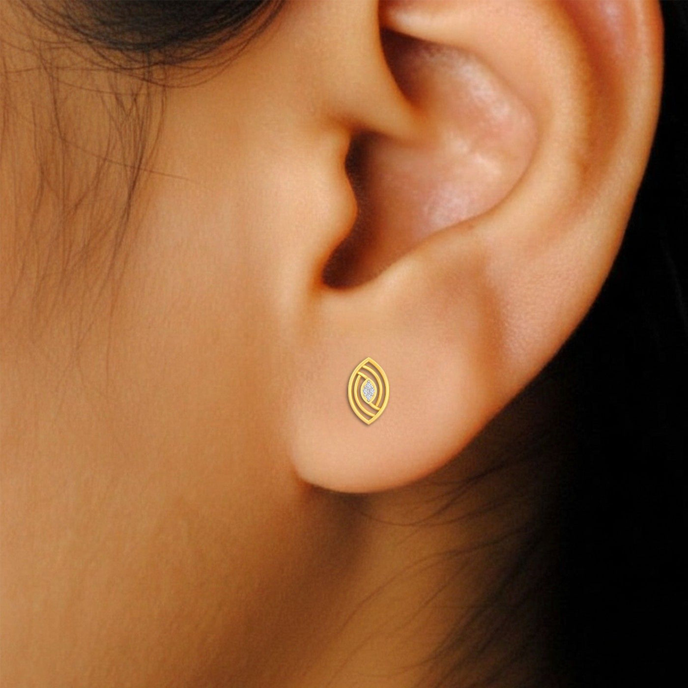 Close-up of an ear wearing a gold and diamond earring with a central diamonds.