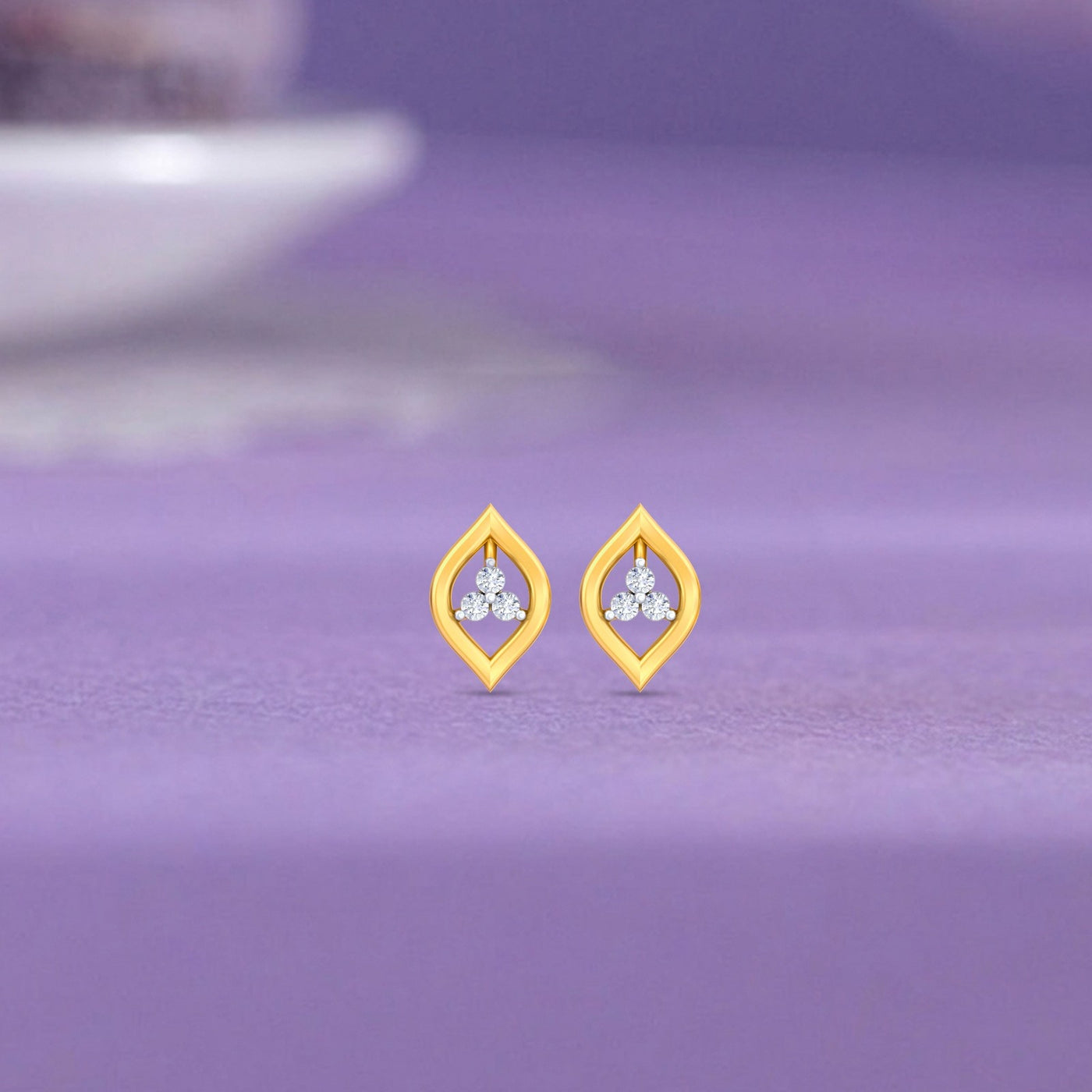 Gold and diamond earrings with marquise on a purple surface