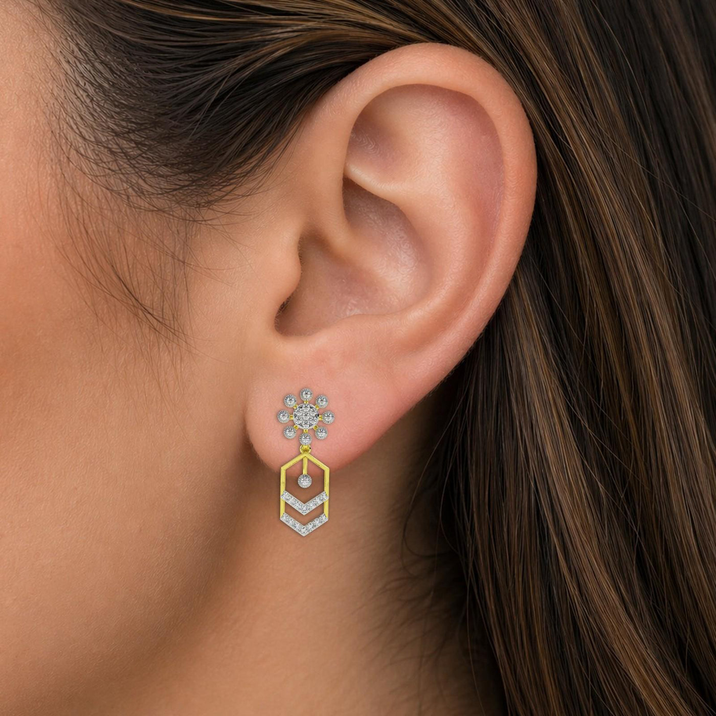 Close-up of an ear wearing a dangler earring with a geometric design.