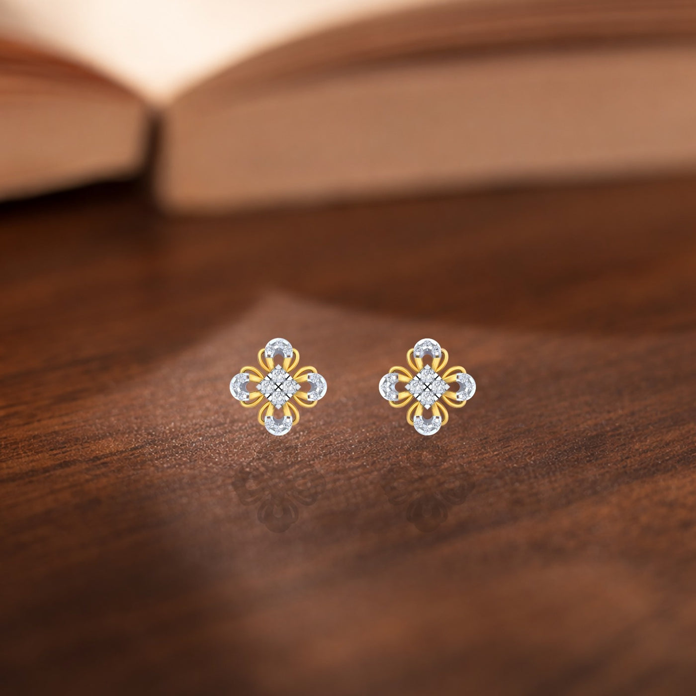 Gold and diamond floral stud earrings on a wooden surface