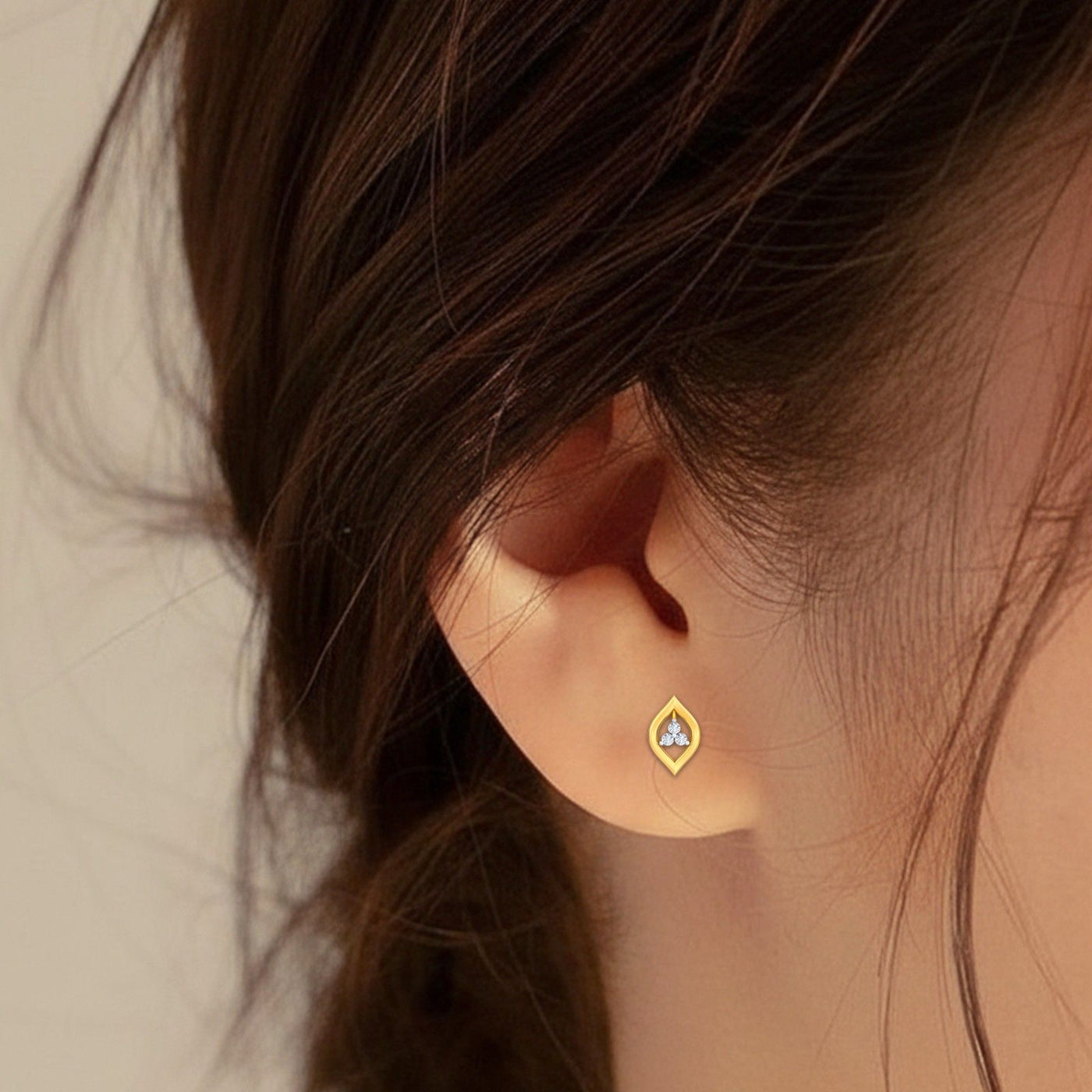 Close-up shot of a gold and diamond stud earring.