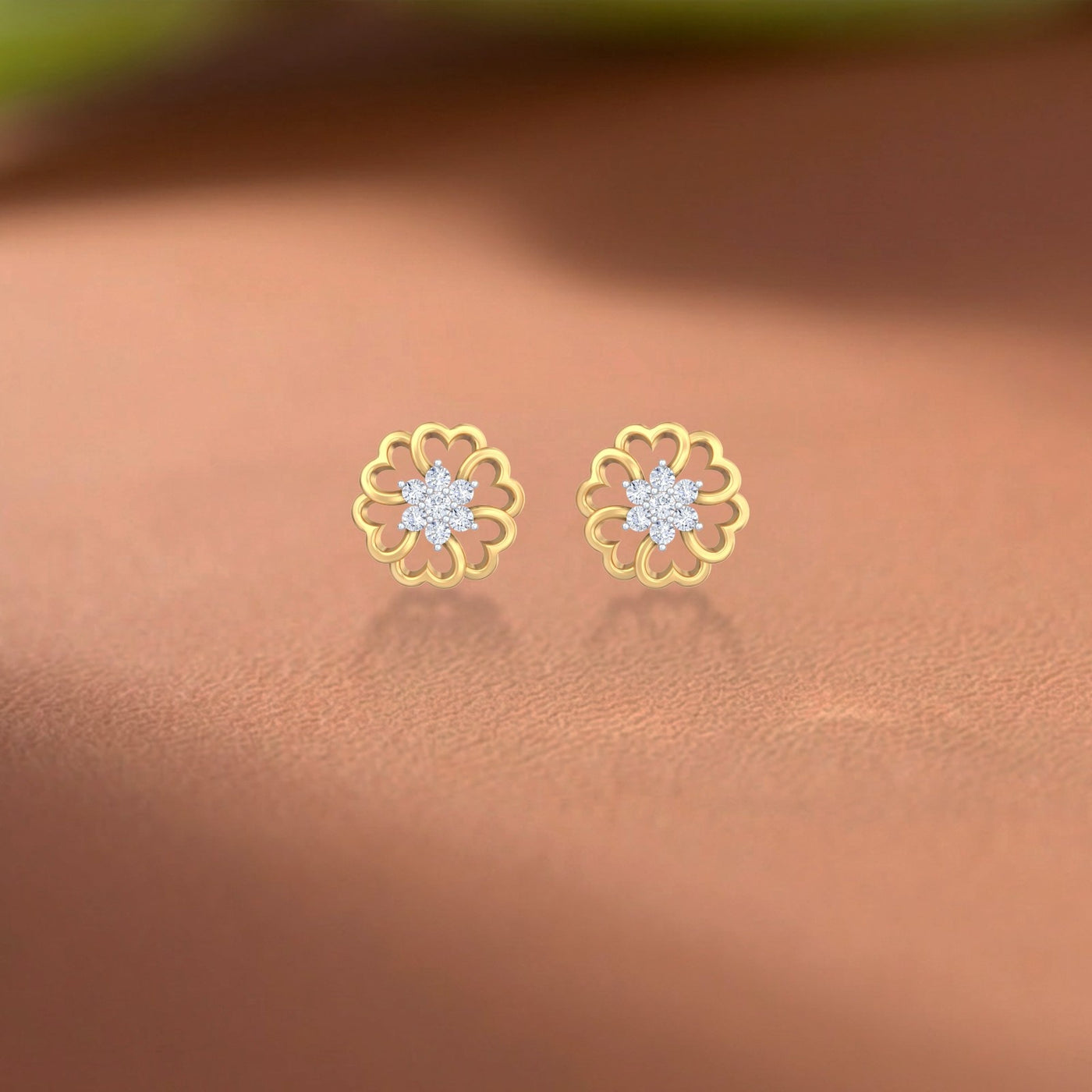 Gold and diamond floral-design stud earrings on a brown surface
