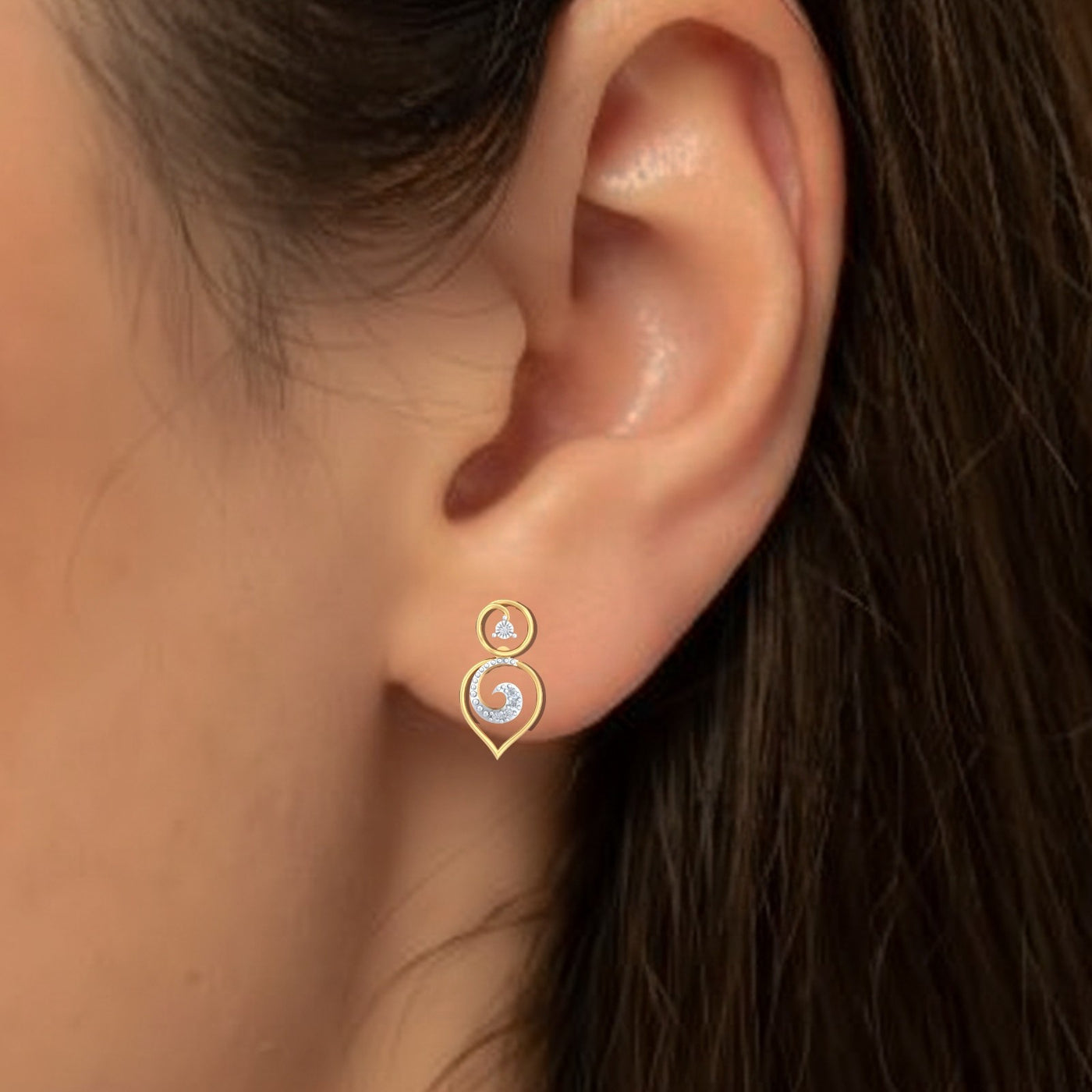 Close-up of an ear wearing a gold and diamond drop earring.