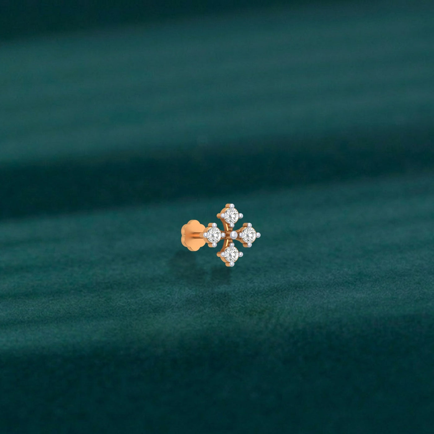 Yellow gold and diamond stud nose pin with clear gemstones on a dark green background