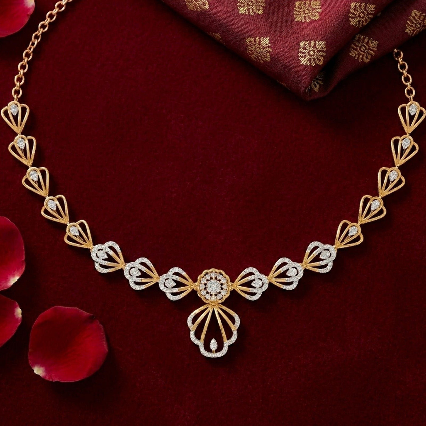 Gold and diamond necklace with a central floral motif, displayed on a deep red velvet background.