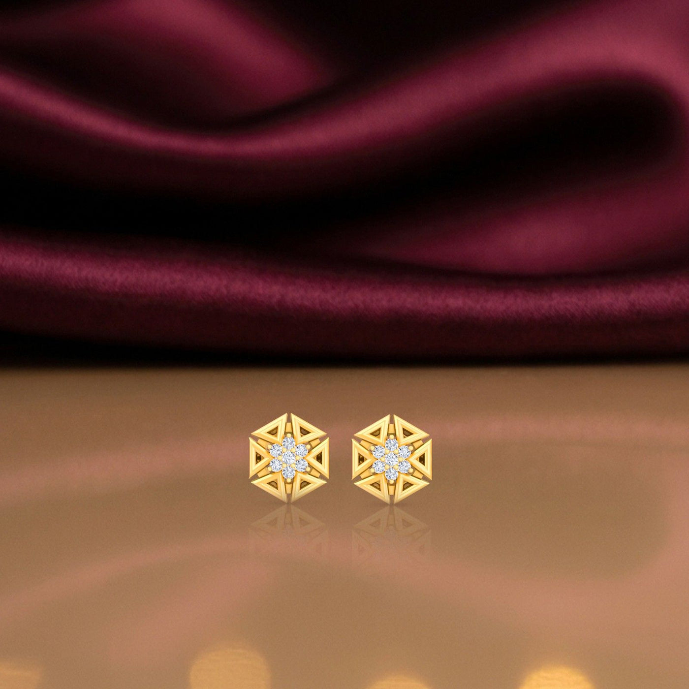 Gold and diamond earrings on a reflective surface.
