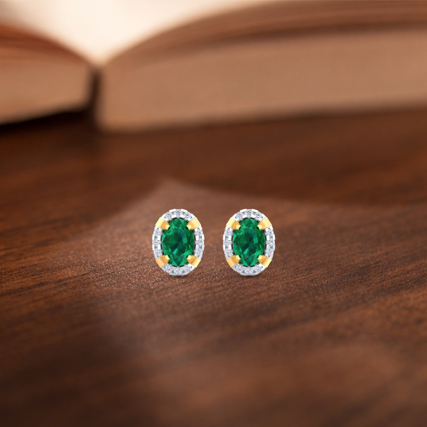 Gold and diamond stud emerald gemstone earrings on a wooden surface.