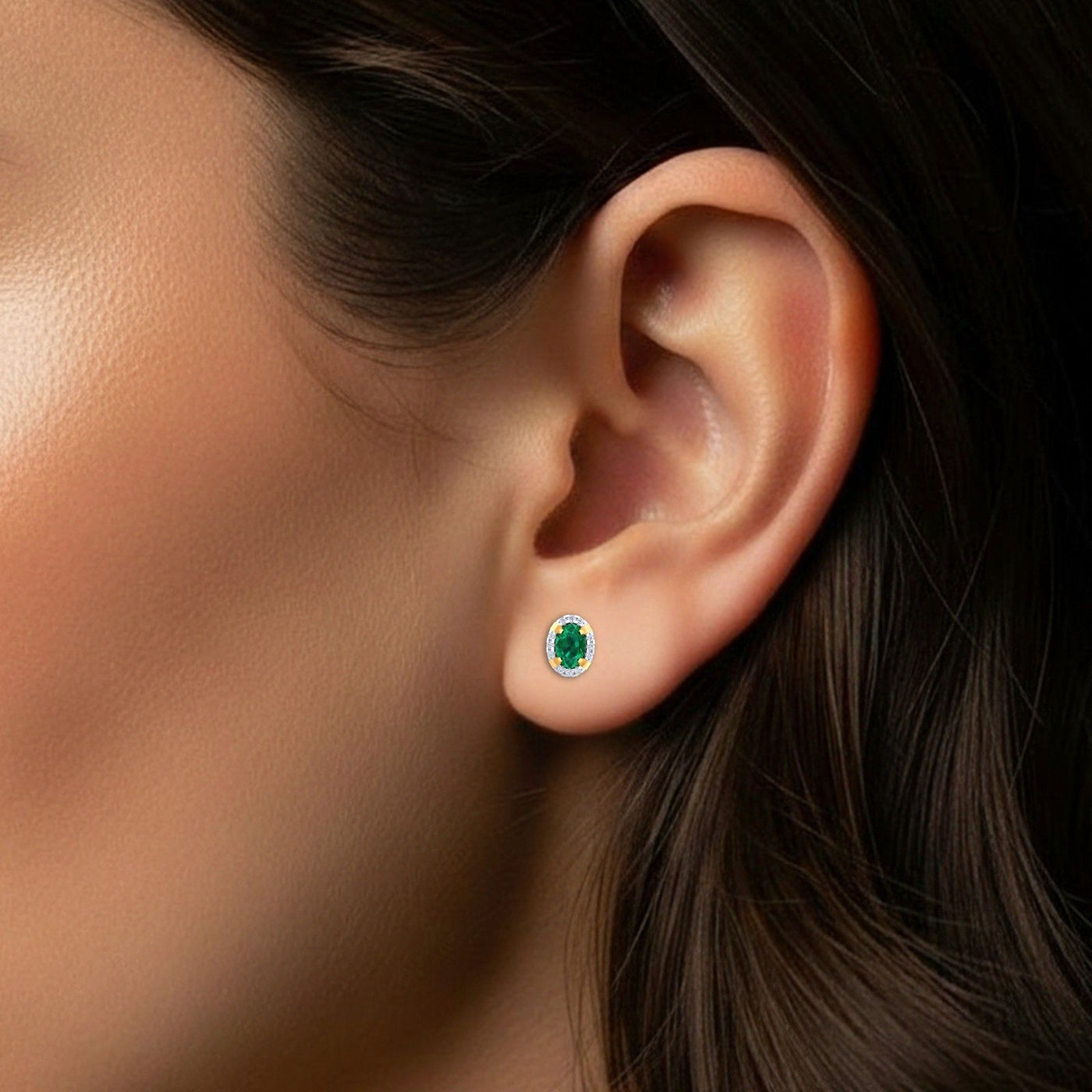 Close-up of an ear wearing a emerald gemstone stud earring.