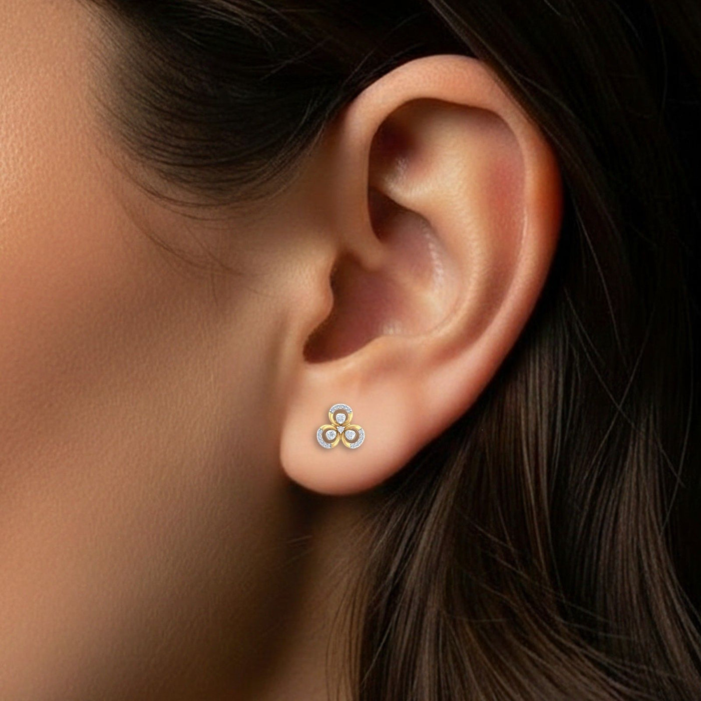 Close-up of an ear wearing a gold and diamond floral stud  earring.