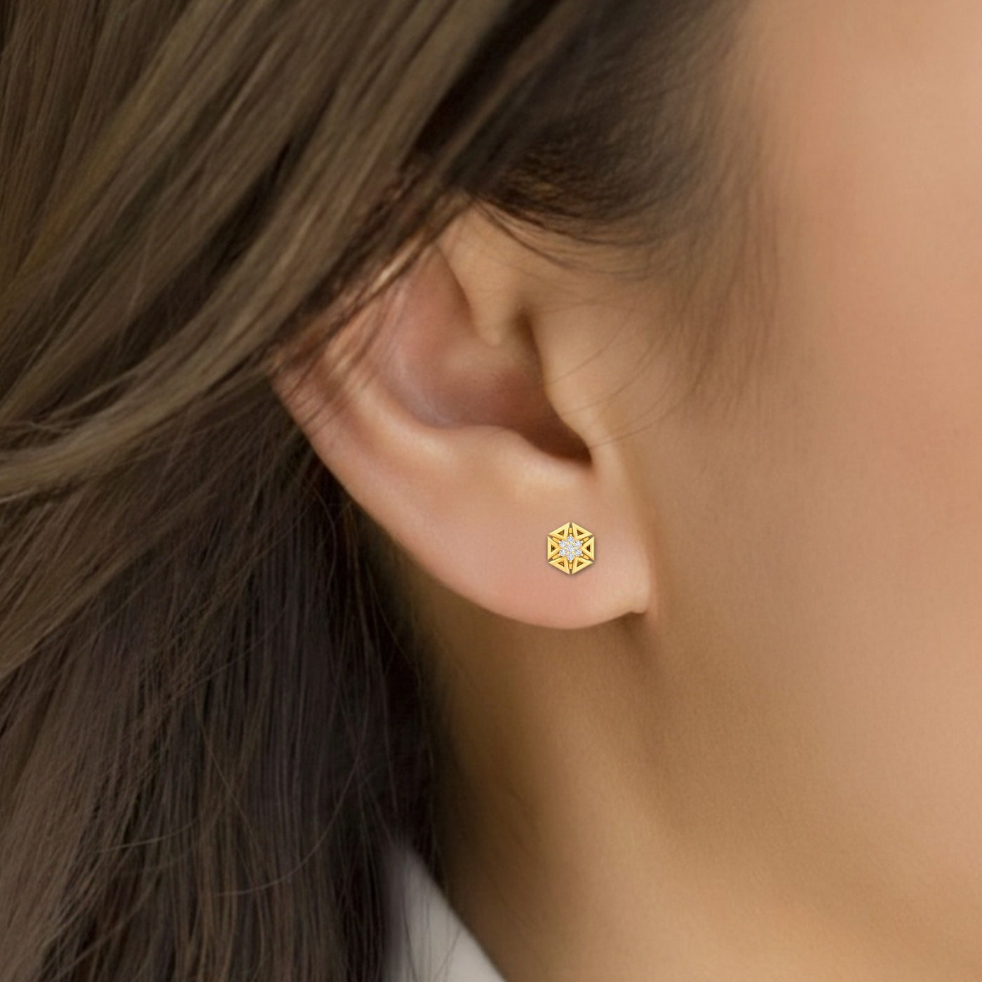 Close-up shot of a gold and diamond stud earring.