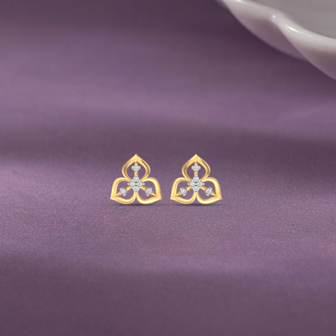 Gold and diamond earrings on a purple fabric background.