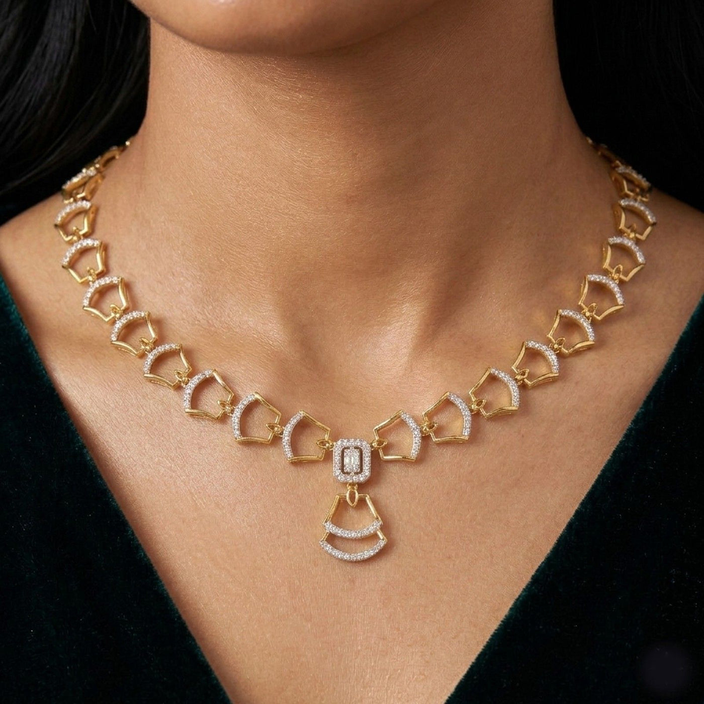 Gold necklace with diamond accents on a person wearing a dark green dress.