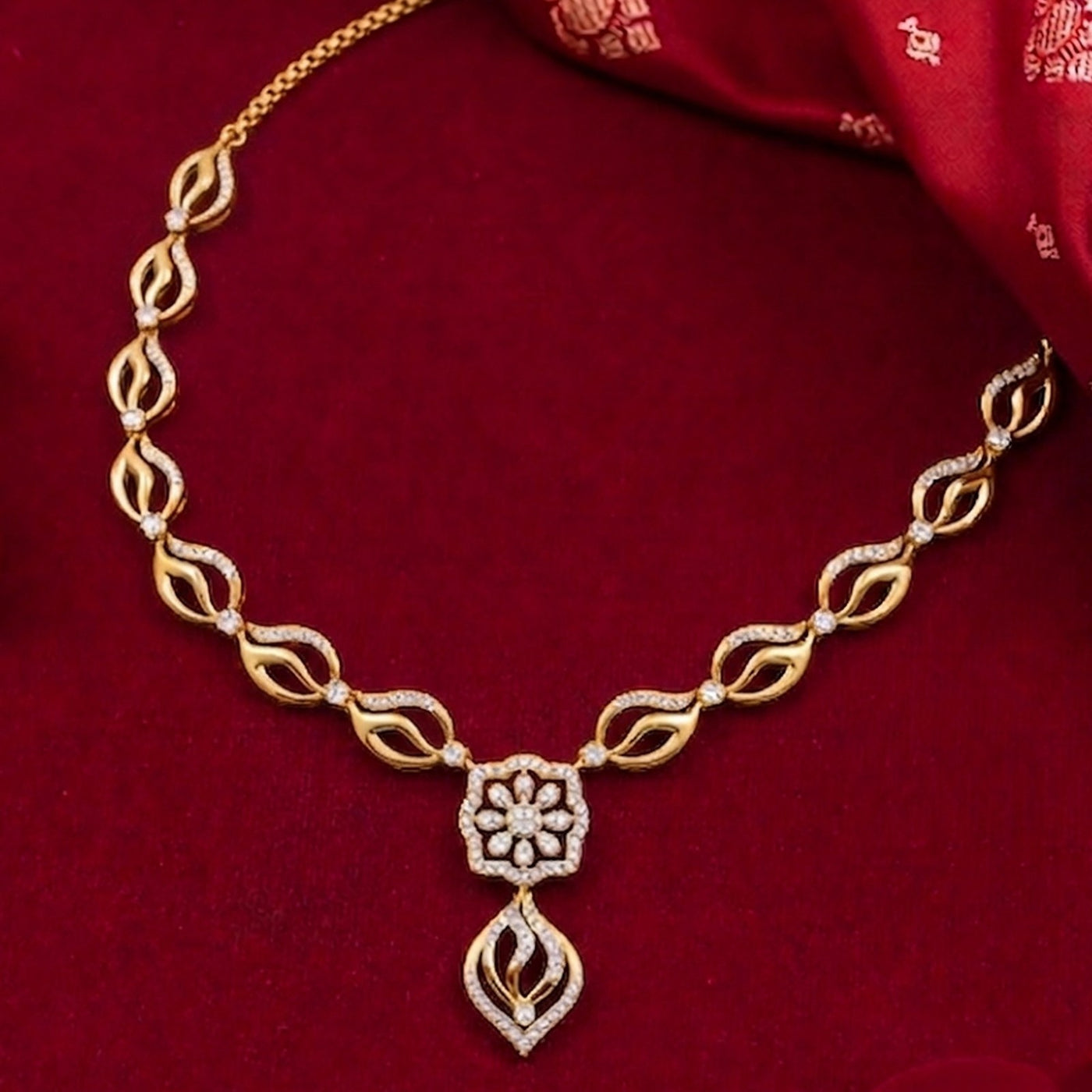 Gold necklace with floral pendant on a red fabric background
