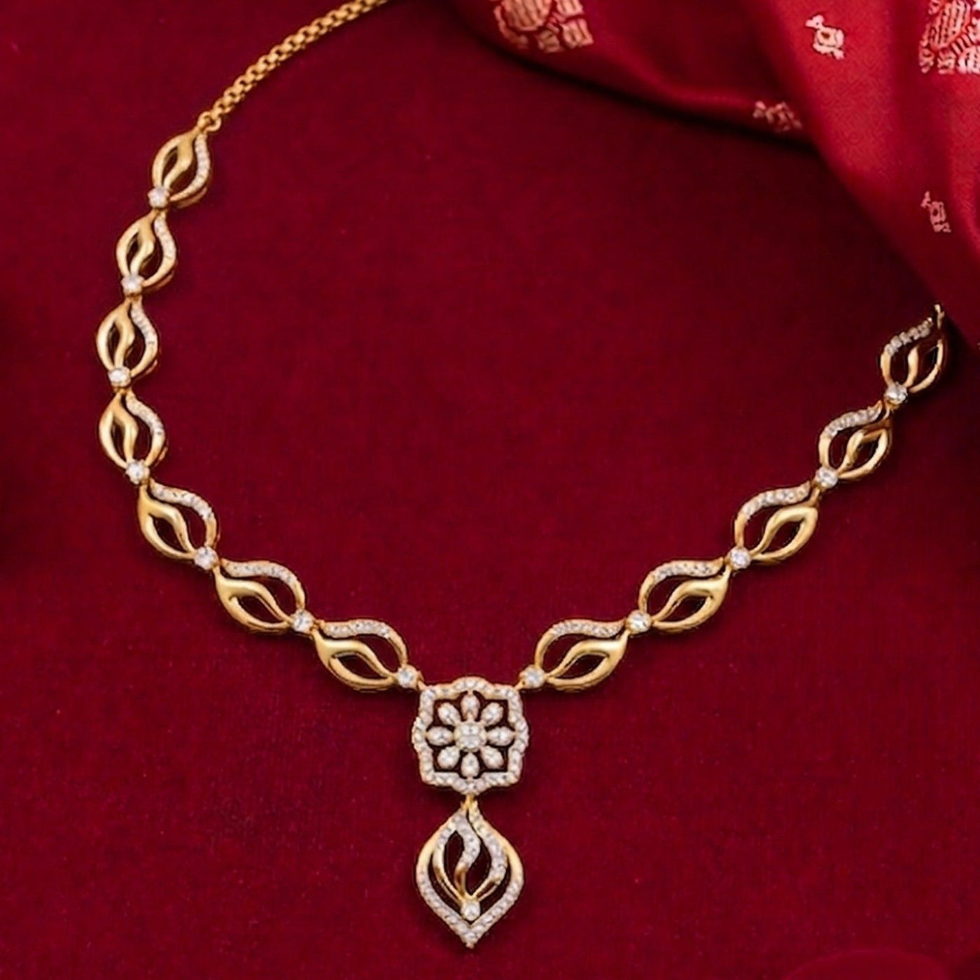 Gold necklace with floral pendant on a red fabric background