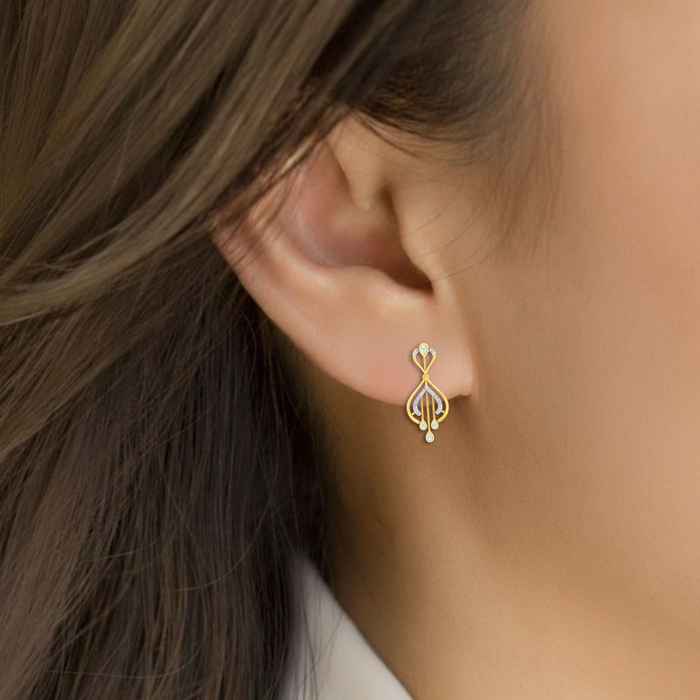A close-up of a woman's ear wearing a gold and diamond drop earrings.