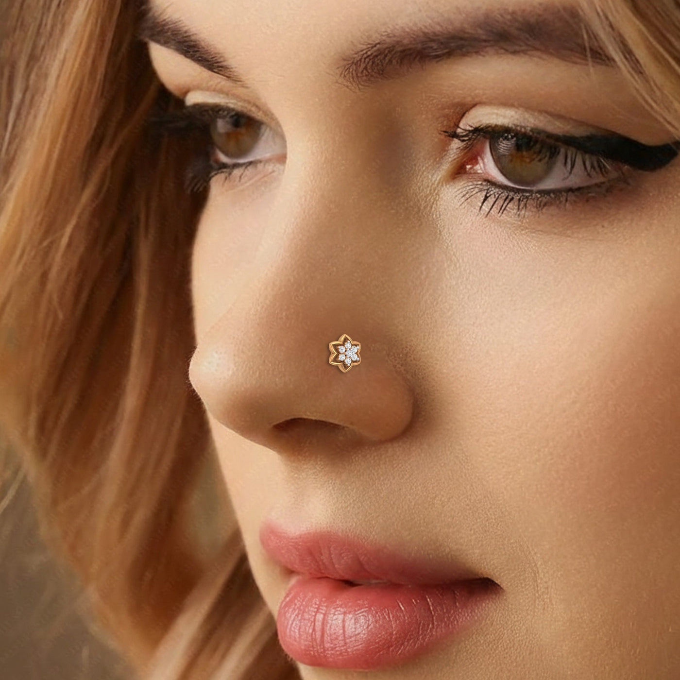 Close-up of a woman's face wearing a gold nose pin with a diamond.