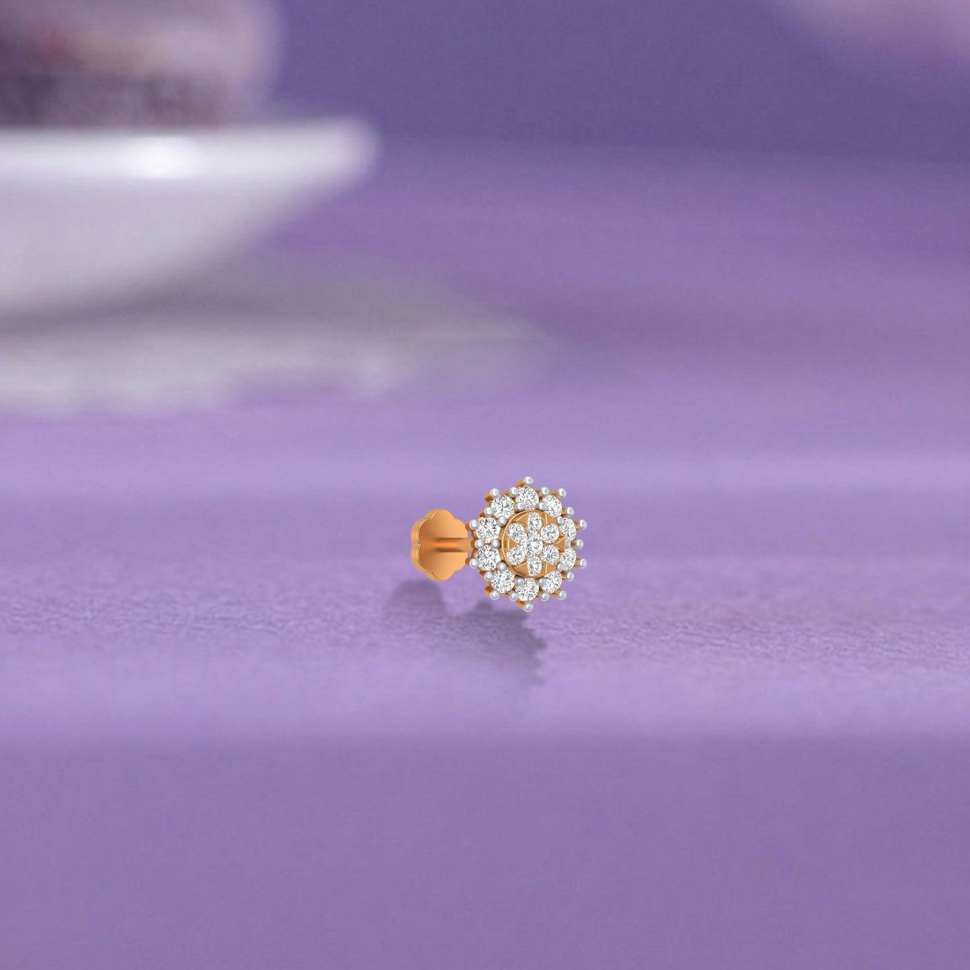 yellow gold and diamond stud nose pin with clear stones on a purple surface