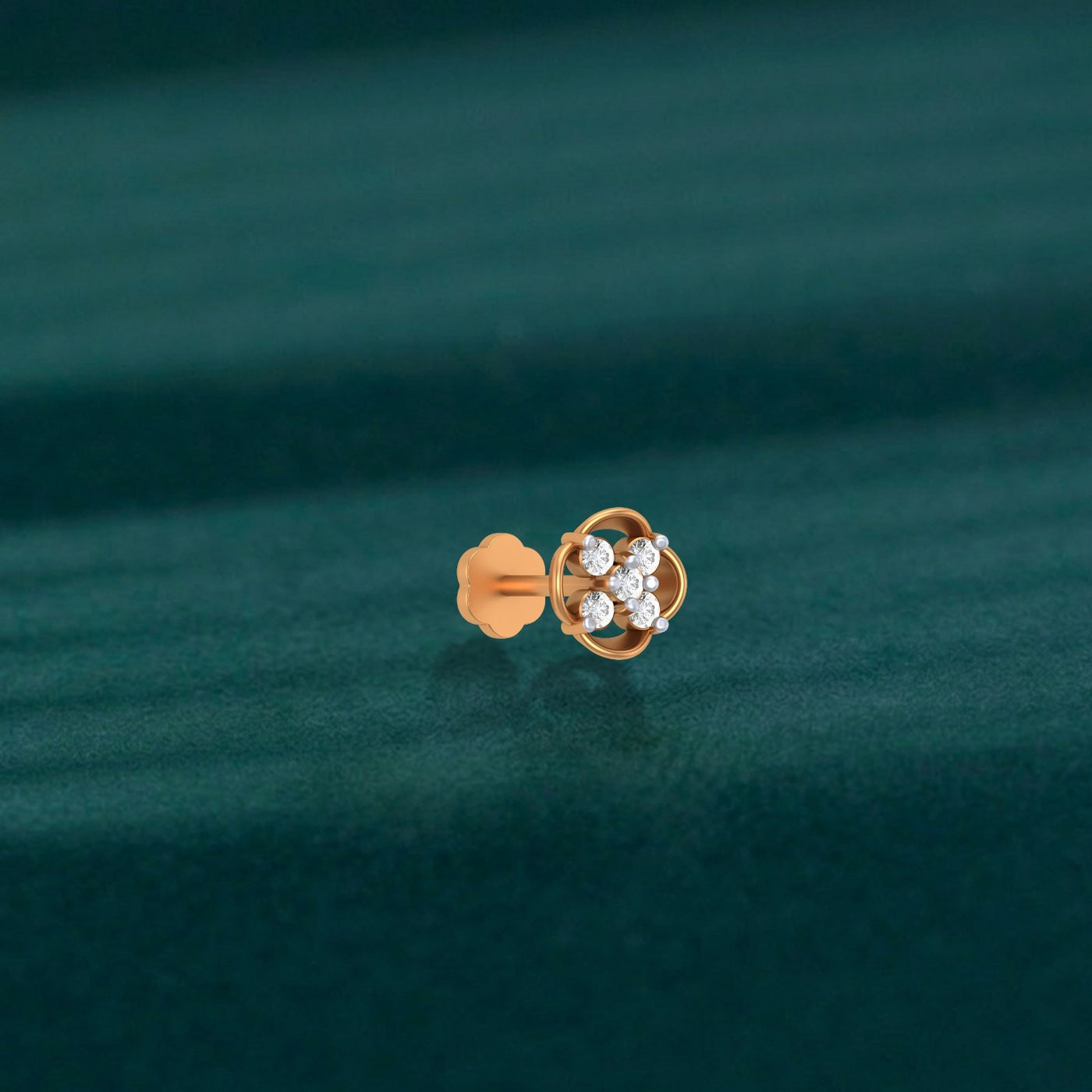 yellow gold and diamond stud nose pin with embedded diamonds on a teal fabric background