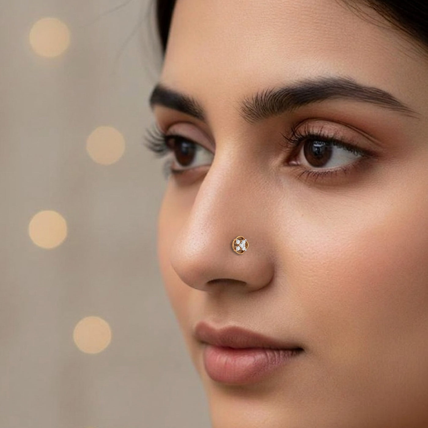 Close-up of a woman's face with a gold nose pin against a beige background