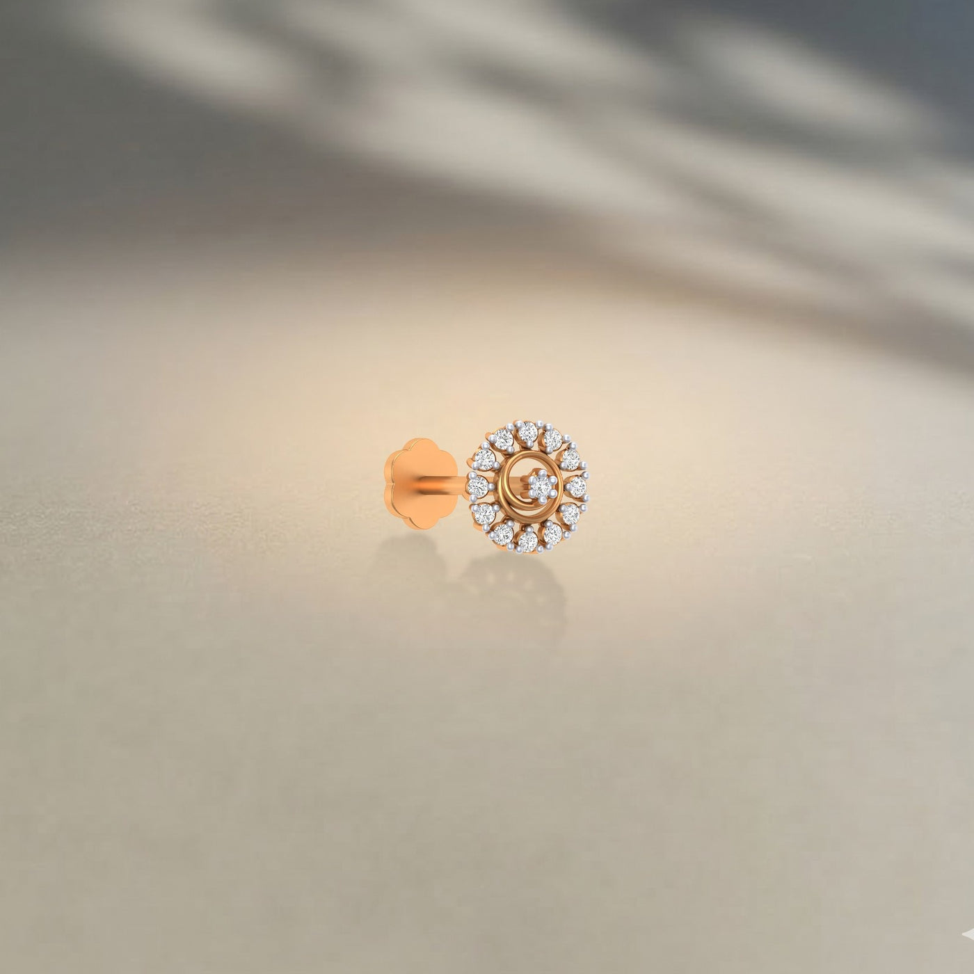 yellow gold and diamond stud nose pin with a central gemstone on a neutral background
