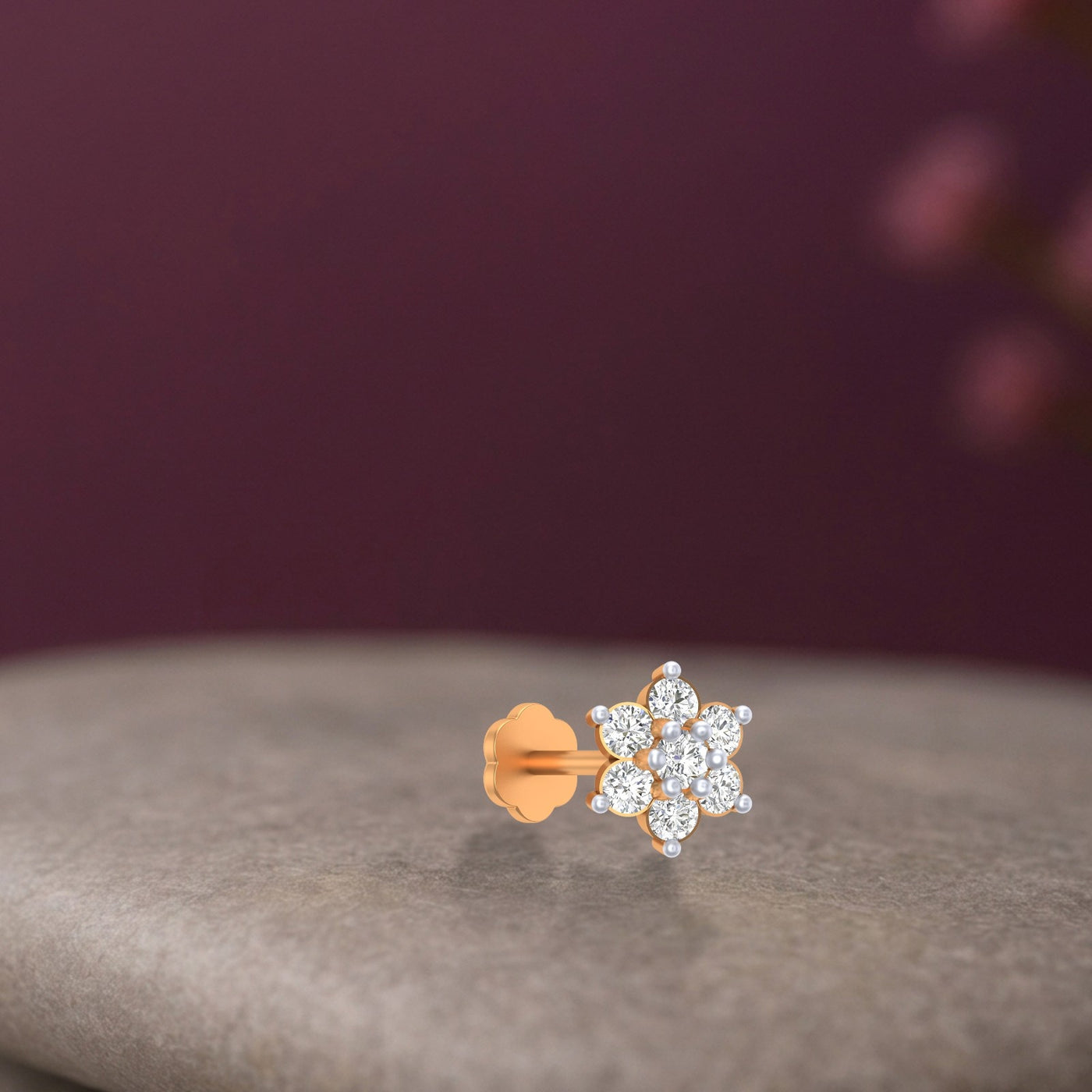 yellow gold and diamond stud nose pin with clear gemstones on a gray surface and purple background