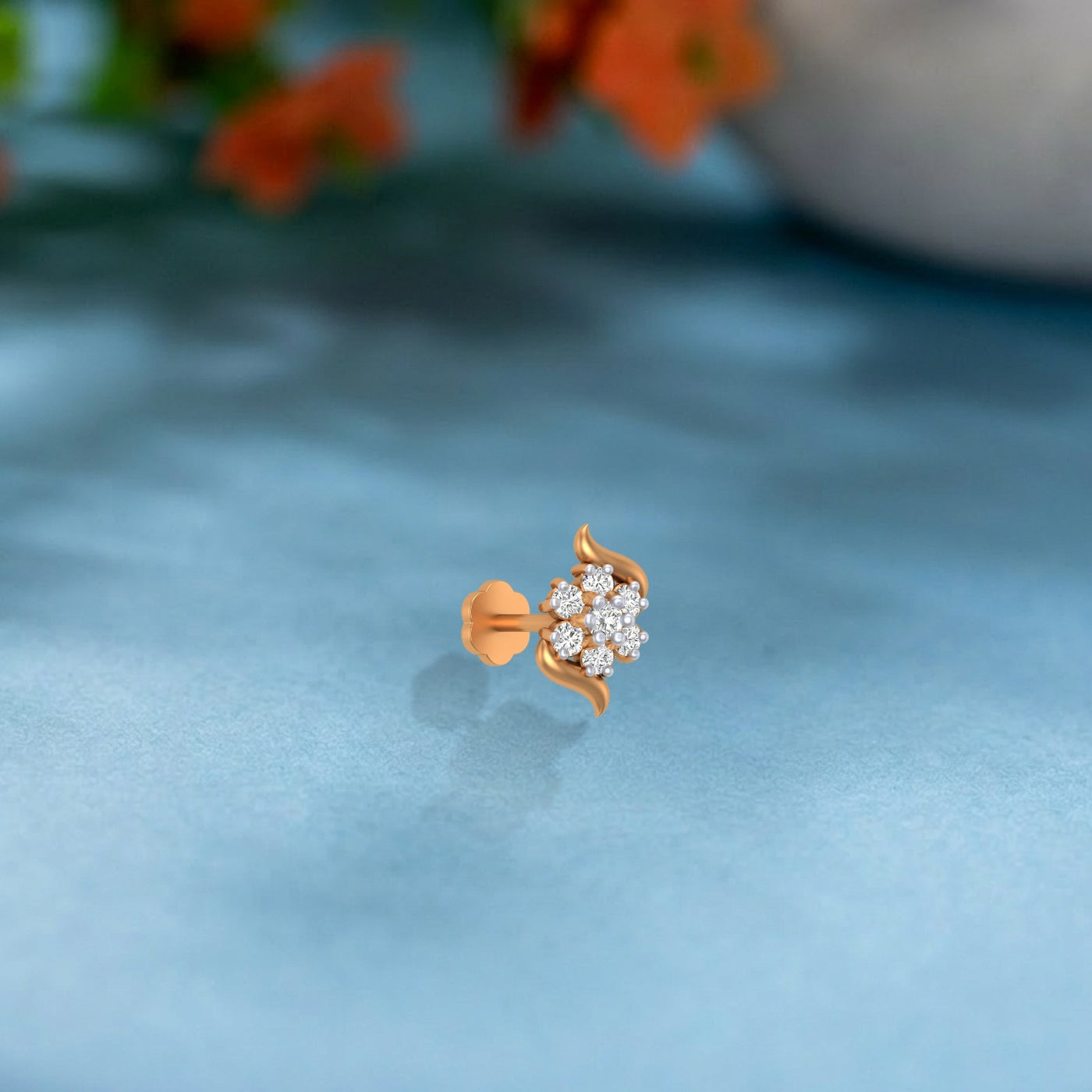 yellow gold and diamond stud nose pin with floral design on a light blue surface