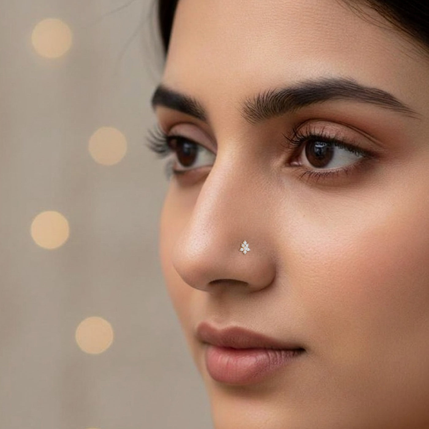 Close-up of a woman's face with a nose pin against a neutral background