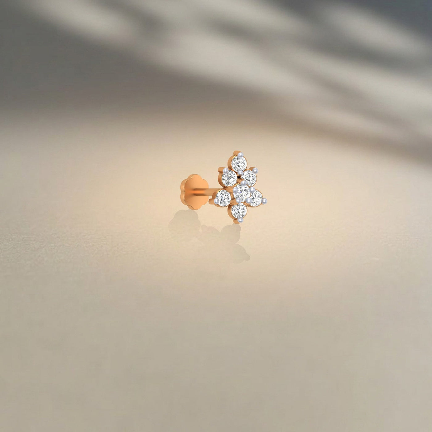yellow gold and diamond stud nose pin with diamonds on a beige background
