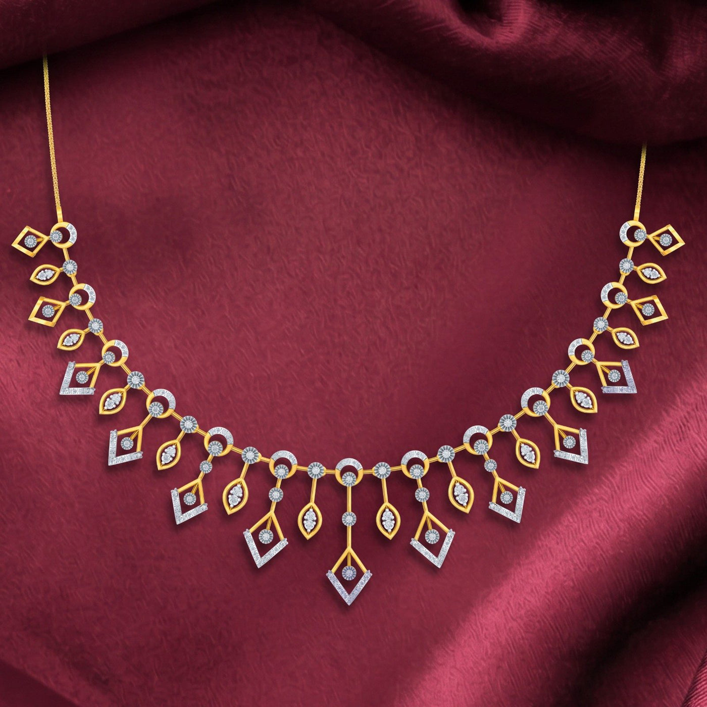 Gold and diamond necklace draped on a deep burgundy satin fabric background.